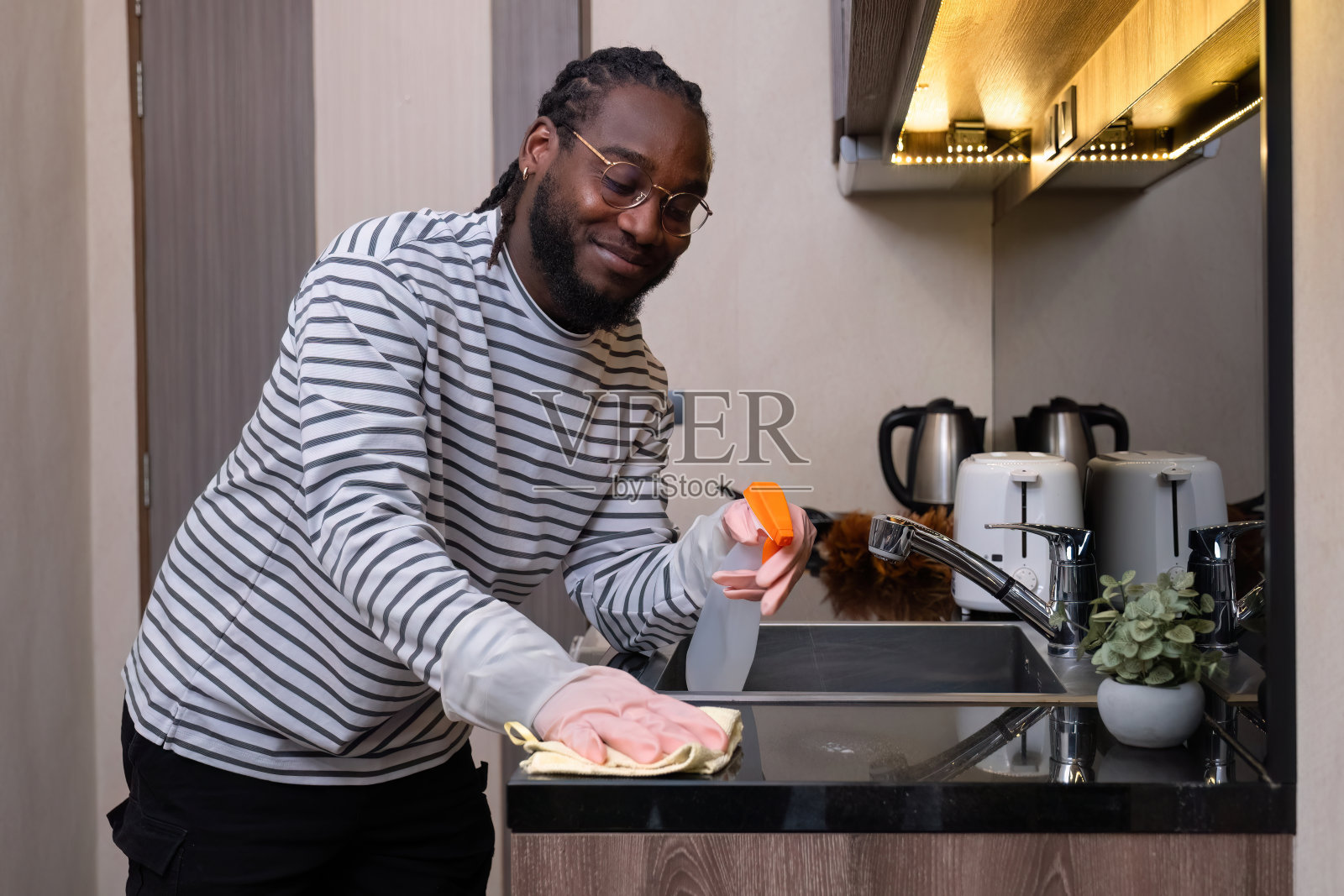 快乐的年轻非裔美国人在家里穿好衣服，在休息日做家务，拖地，打扫房间。照片摄影图片