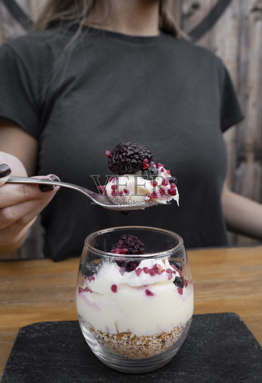 一个女人的特写镜头，她正在享用玻璃杯里美味健康的甜点照片摄影图片