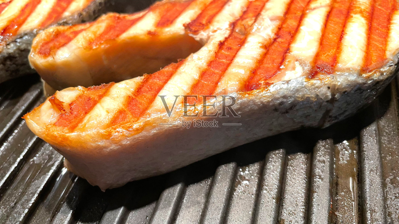 三文鱼排，用香草在烤盘上烤。黑色背景。俯视图照片摄影图片