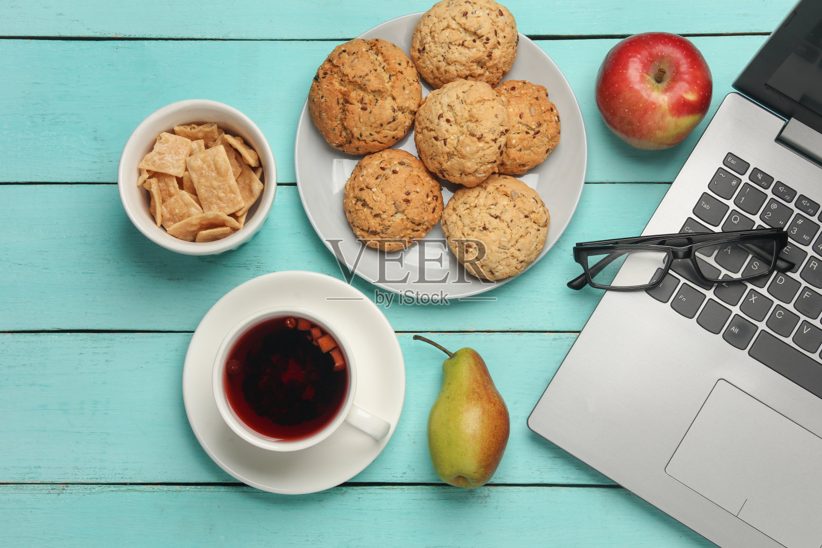 一杯茶，饼干，水果和笔记本电脑放在蓝色的桌子上照片摄影图片