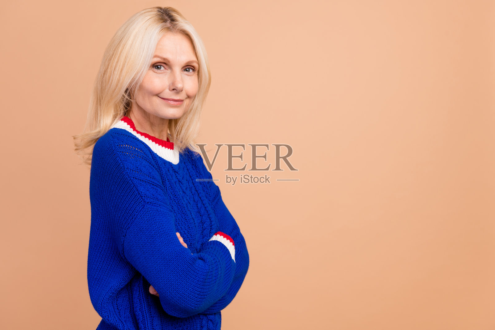 照片中心情好的人，金发碧眼，穿着蓝色套头衫，手掌折叠，靠近米色背景上孤立的空白空间照片摄影图片