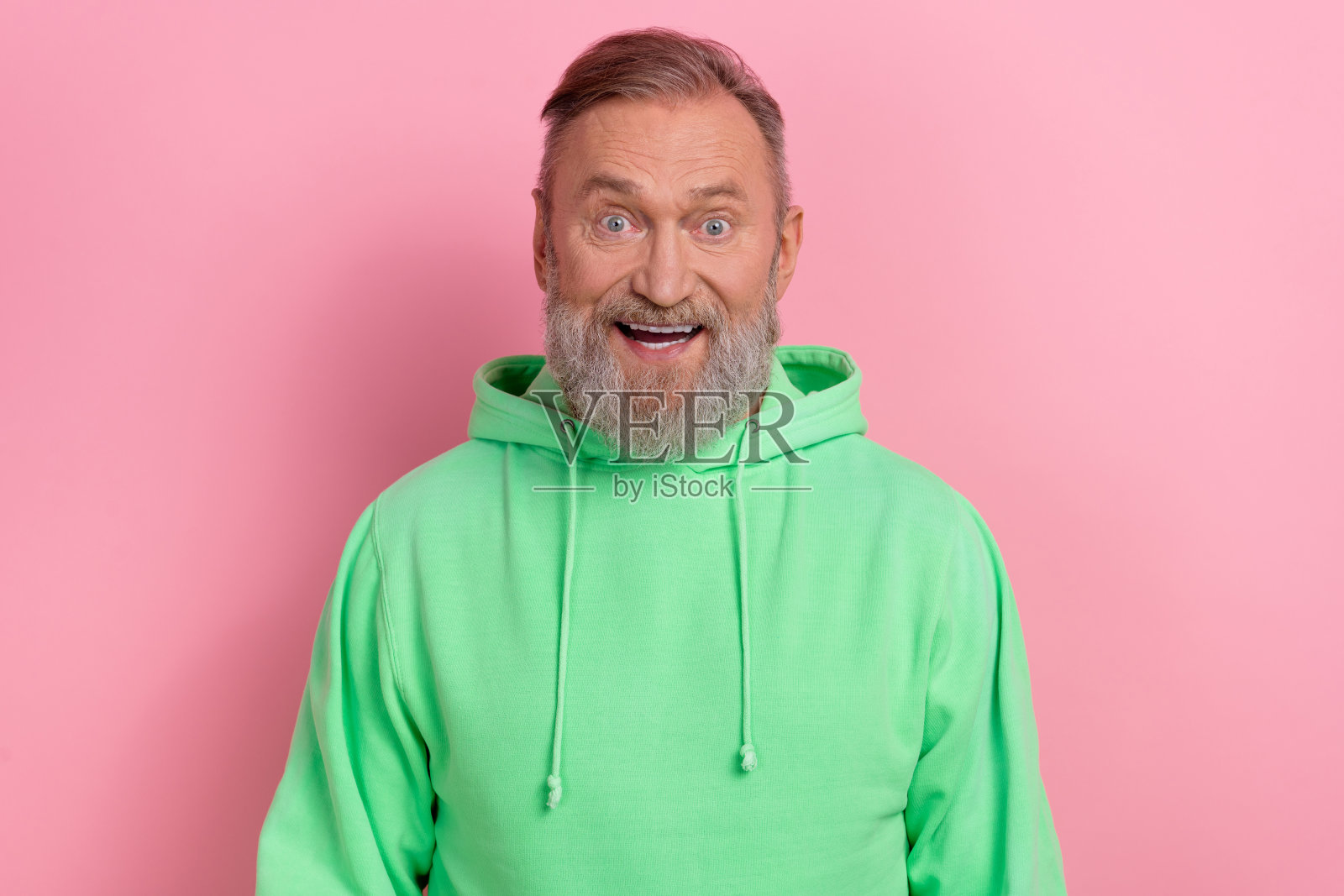 照片中兴奋时髦的男子穿着绿色运动衫大眼睛张开嘴巴孤立的粉红色背景照片摄影图片