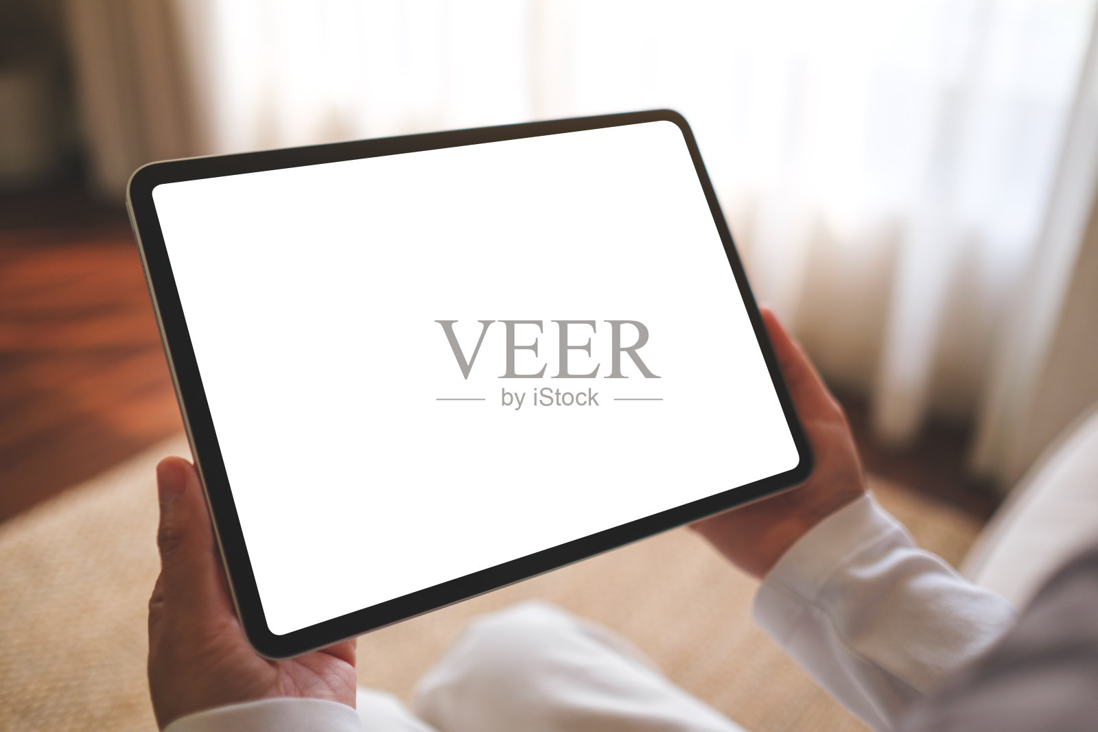 一个女人坐在家里的沙发上，拿着空白桌面的数字平板电脑的模拟图像照片摄影图片