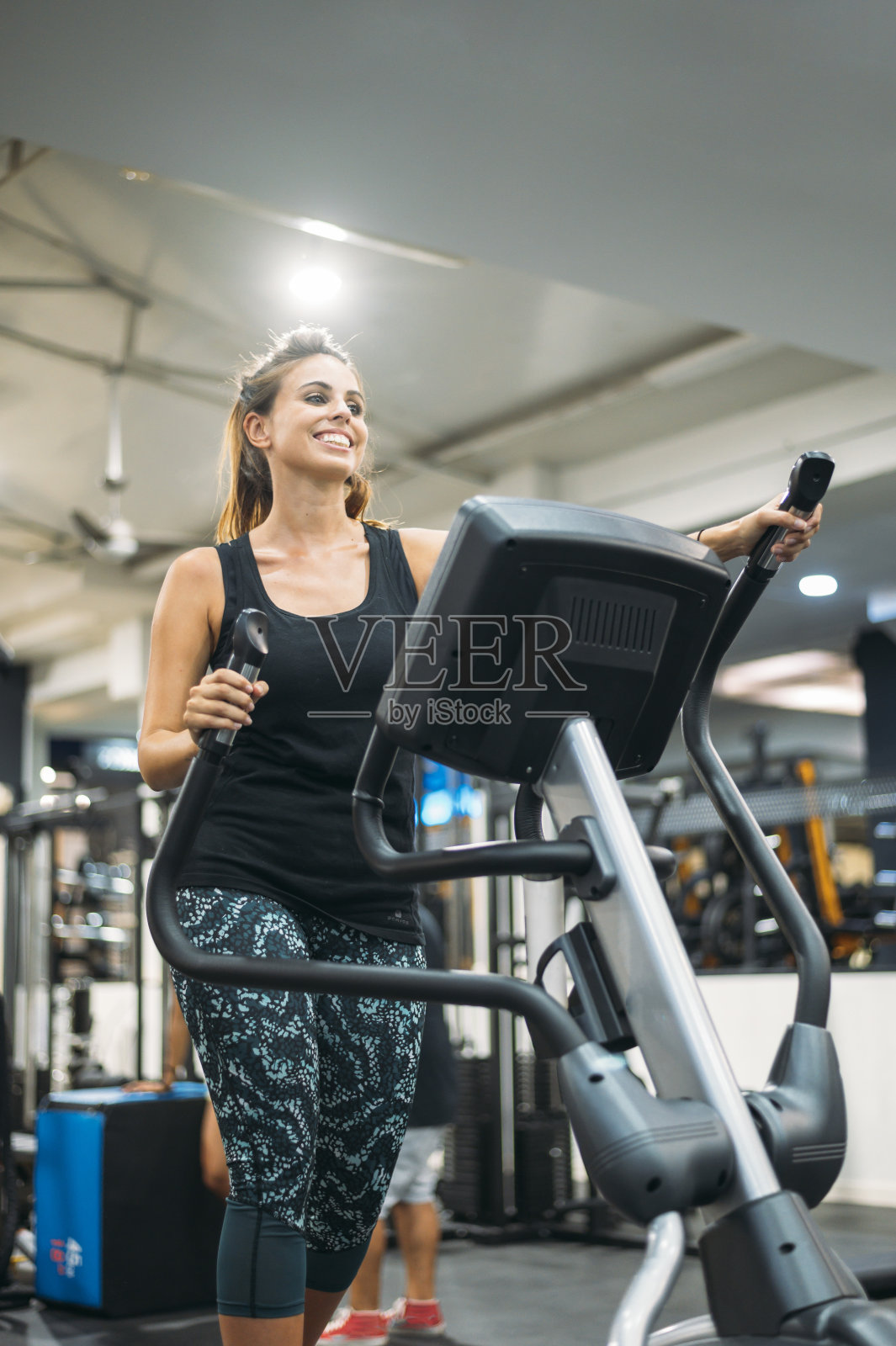 为了健康的生活方式理念，一位女士正在健身房里的阶梯攀登机上锻炼。照片摄影图片