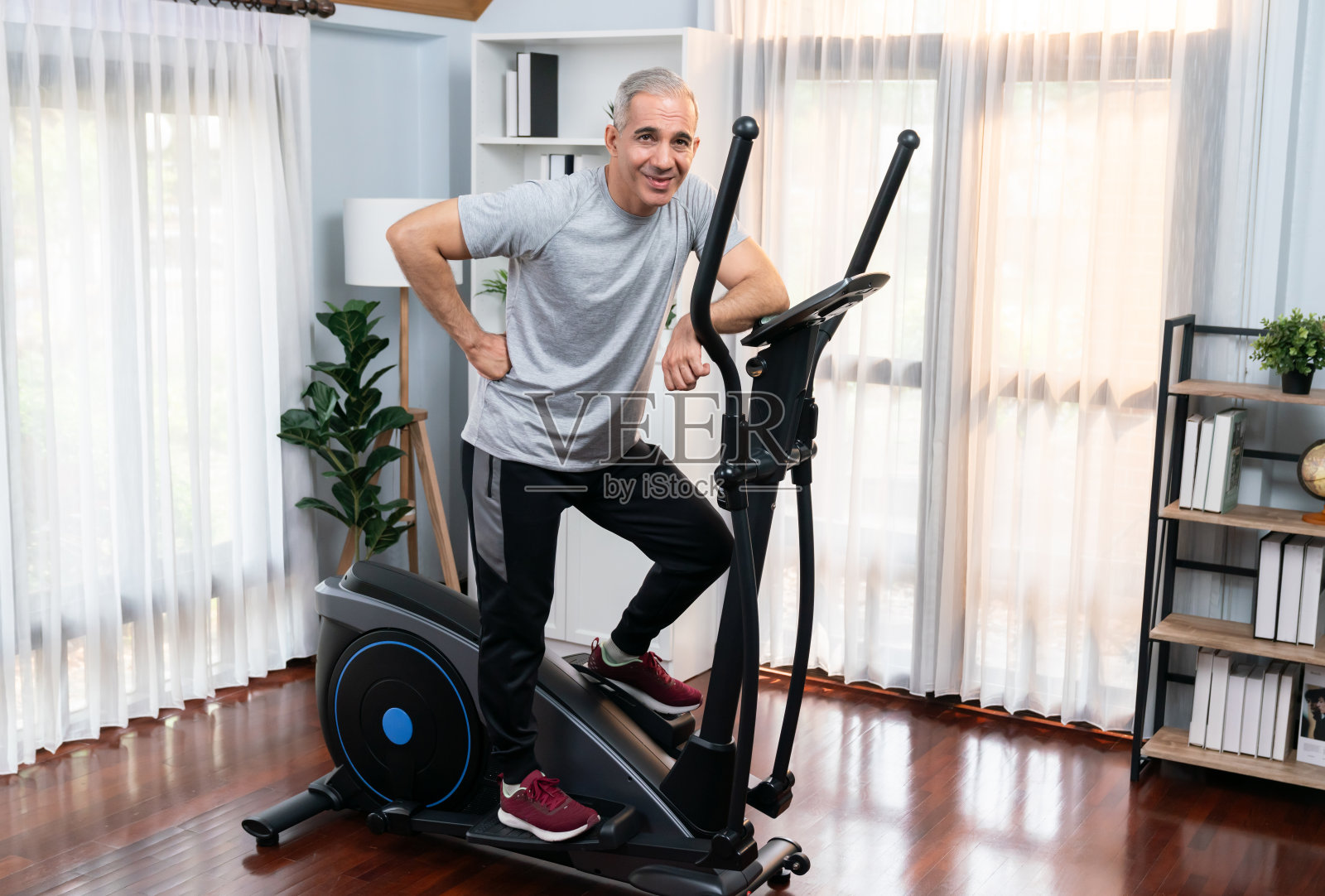 活跃的老年人在椭圆机上跑步。影响力照片摄影图片