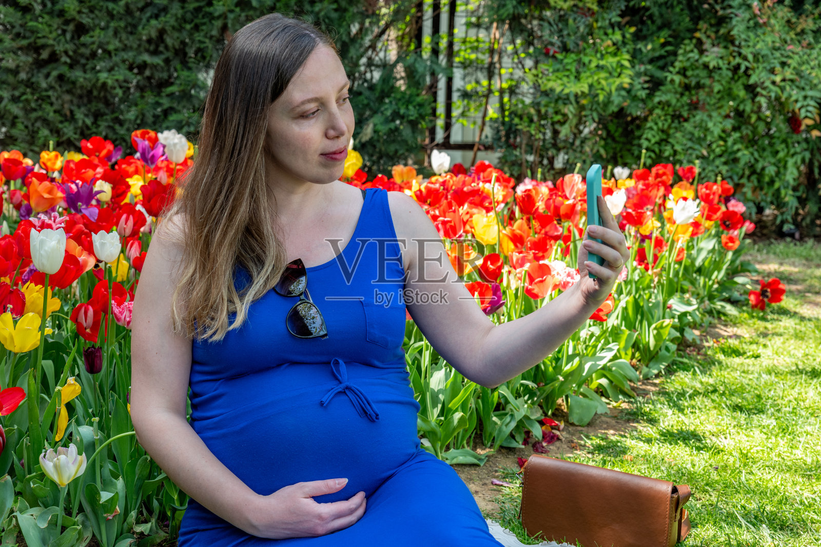 美丽的孕妇在公园里感到可爱和微笑照片摄影图片