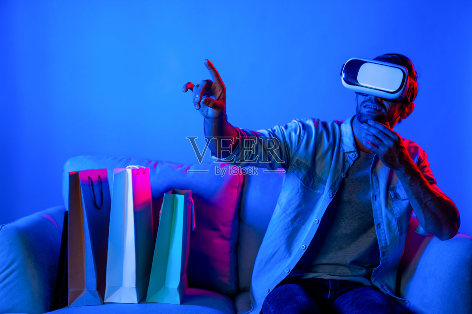 戴vr眼镜的白人男子坐在沙发上选择节目。偏差。照片摄影图片