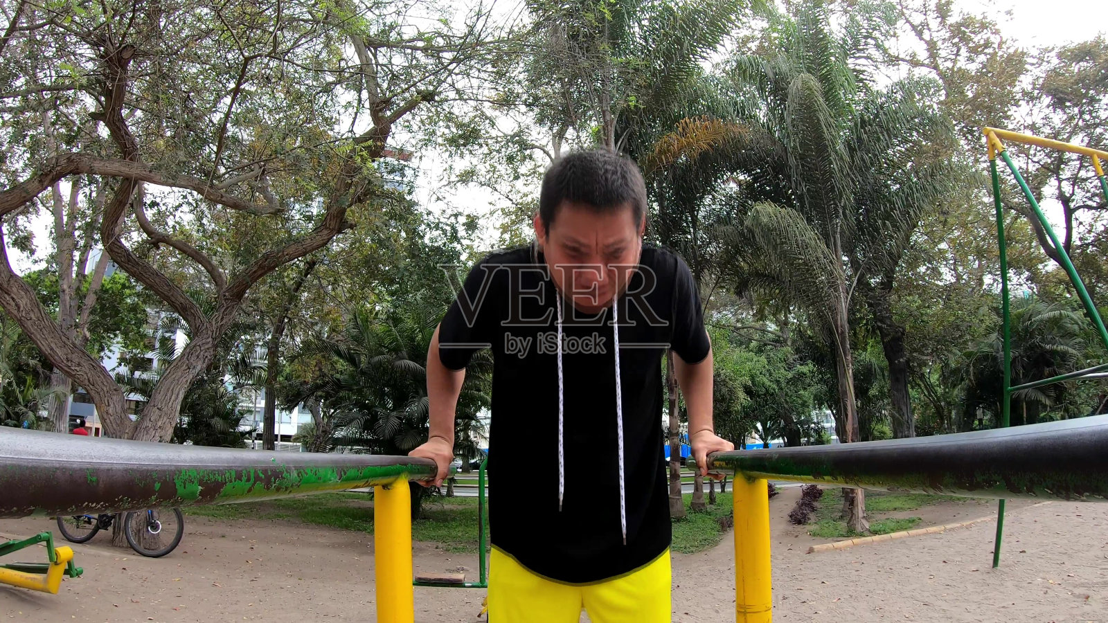 强壮的年轻人正在双杠上做肱三头肌俯卧撑。夏天早上在户外锻炼。动机和运动营养的概念。照片摄影图片