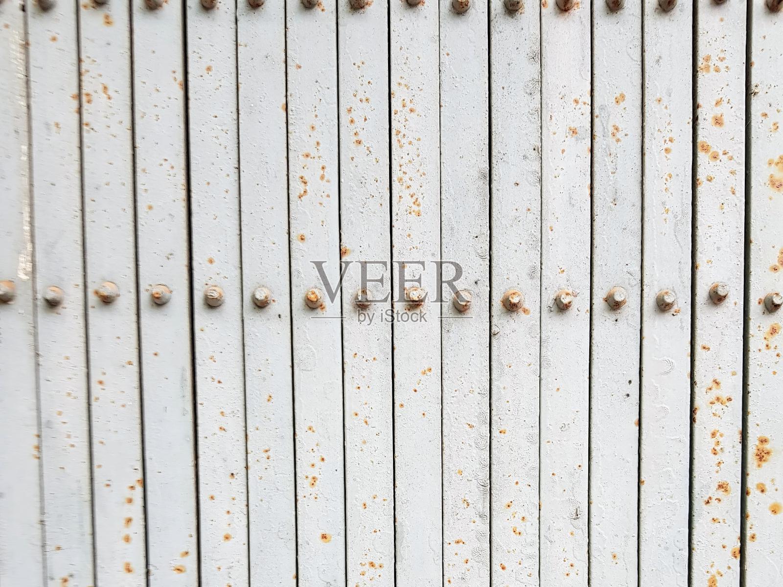 一张有铆钉和铁锈的金属门的照片。照片摄影图片