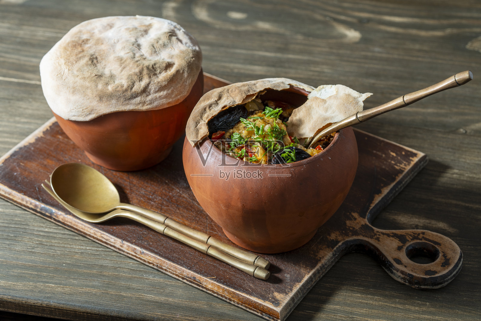 木桌上放着两个炖菜的陶罐，特写。用陶器炖食物被认为是健康的照片摄影图片