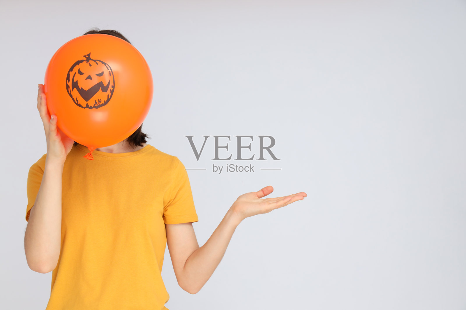 万圣节的概念，女子手持万圣节气球在浅色背景照片摄影图片
