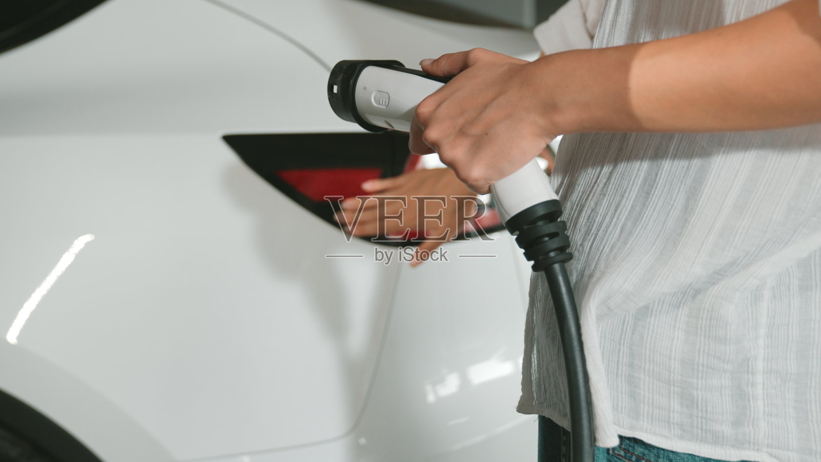 年轻女子驾驶电动汽车前往购物中心停车场内部照片摄影图片