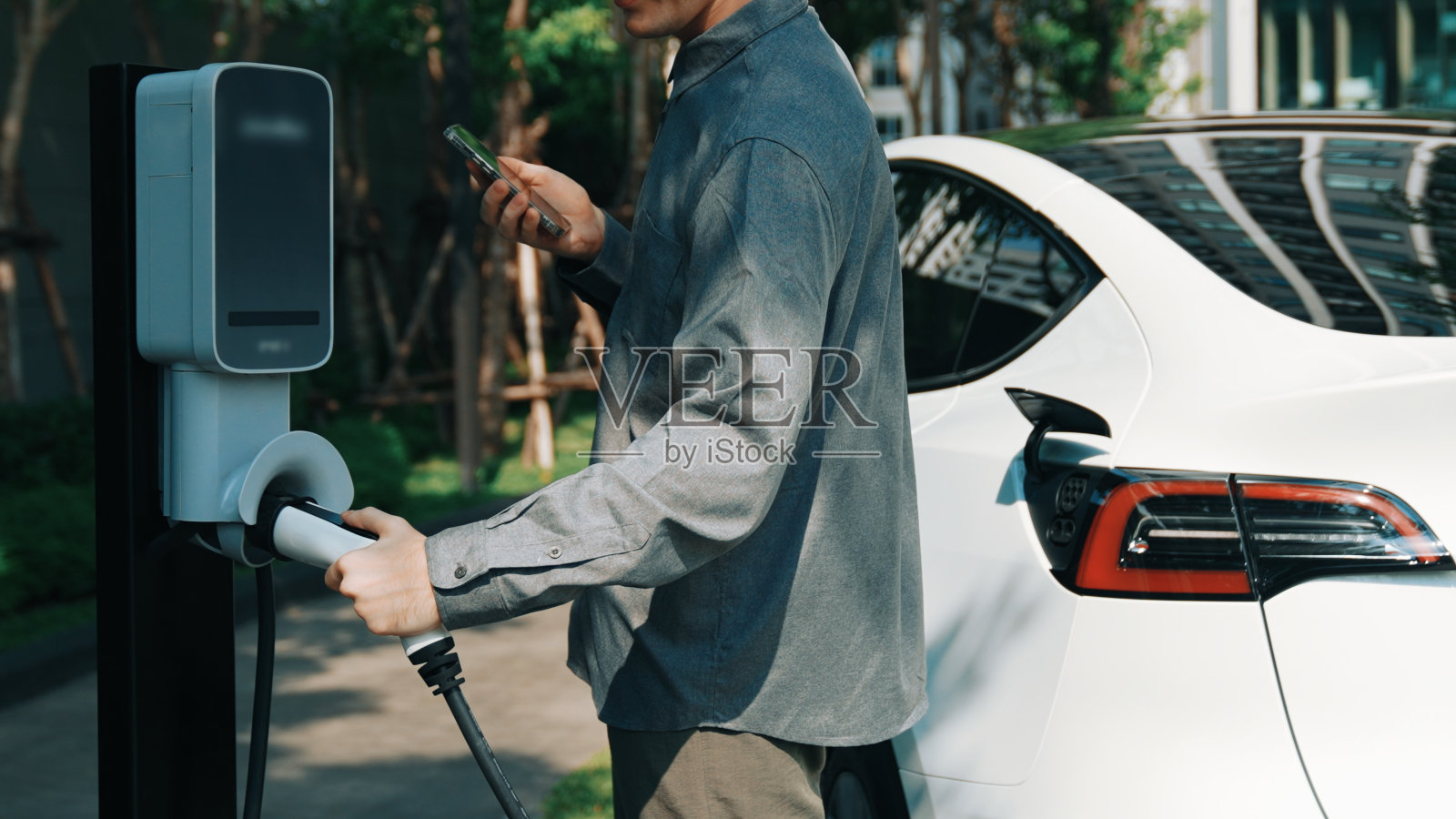 年轻人在公寓内部给电动汽车充电照片摄影图片