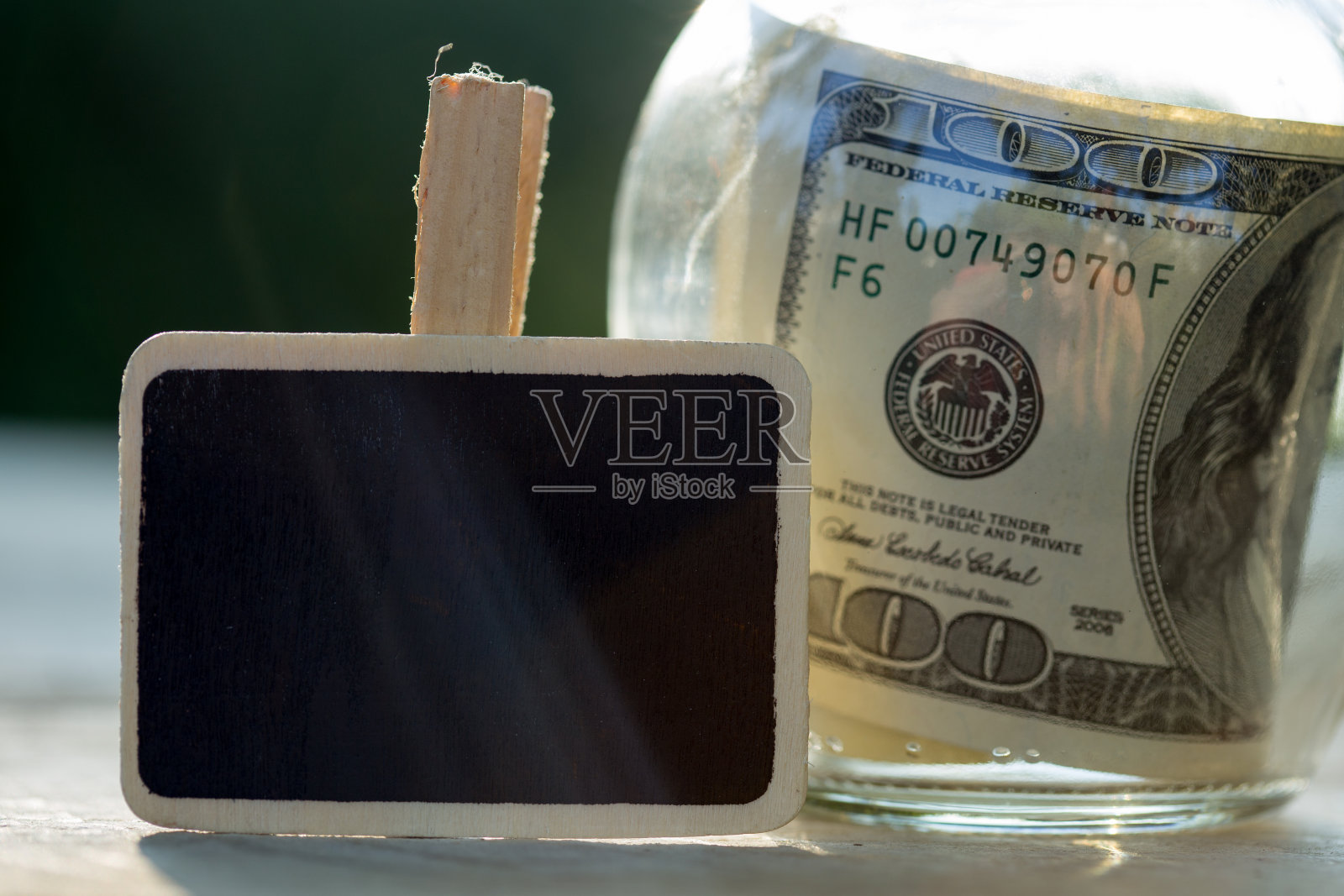 一百美元装在玻璃罐里。绿色背景照片摄影图片