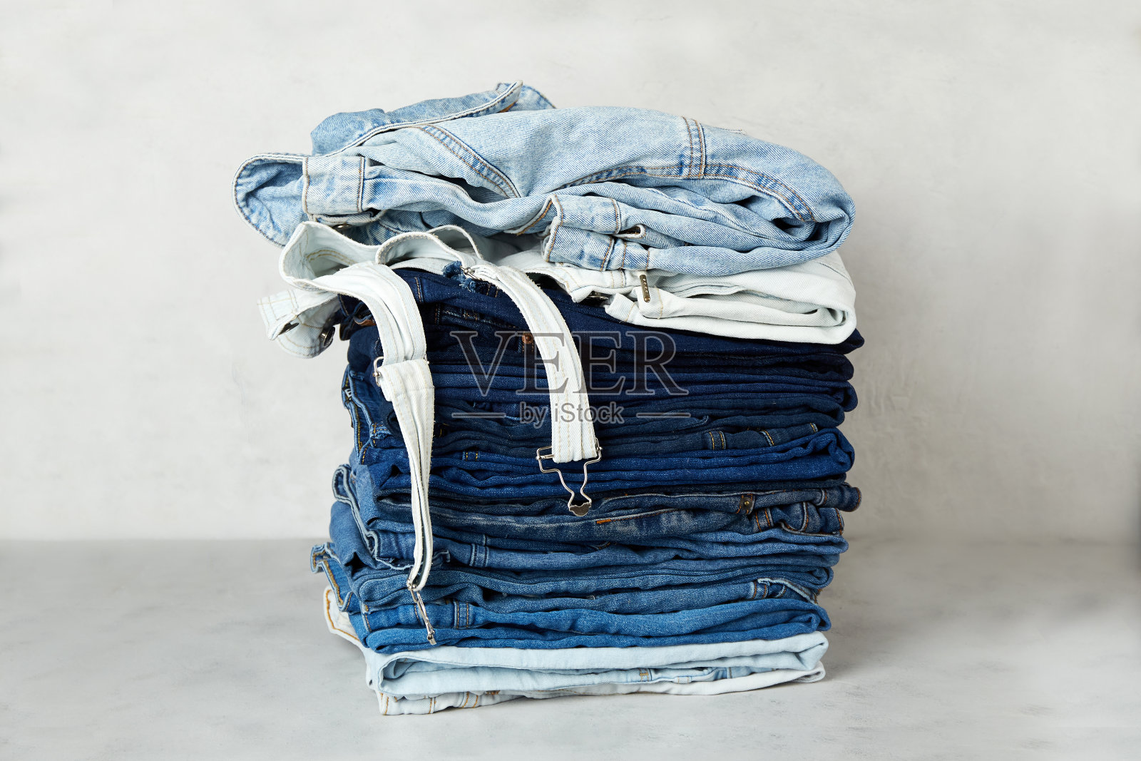 灰色背景上一叠叠好的牛仔衣服照片摄影图片