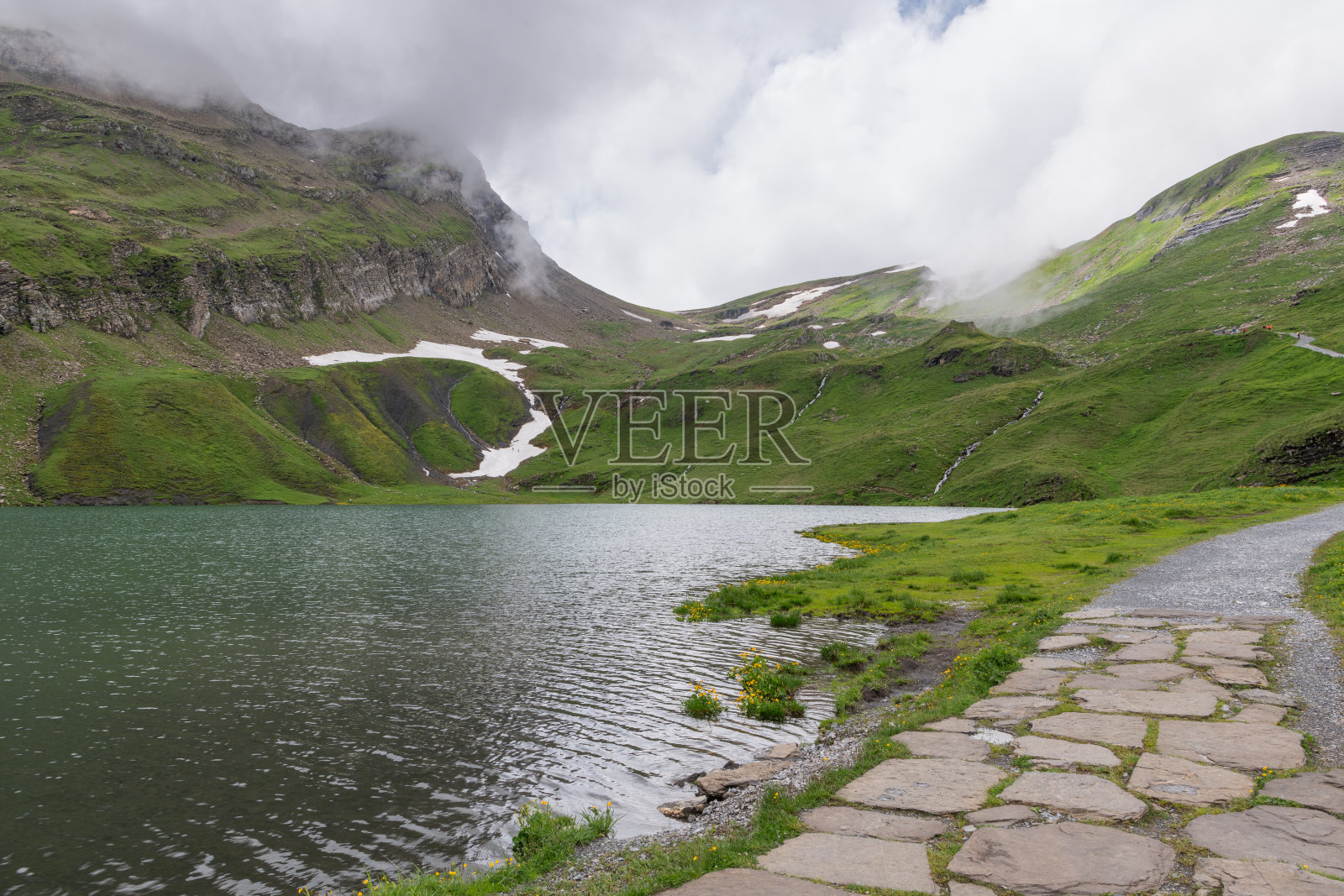 在一个多云的夏日，巴赫湖被瑞士山脉包围。铺好的步行道。瑞士格林德瓦尔附近的高山湖泊。美丽的瑞士高山景观。游客必看景点。照片摄影图片
