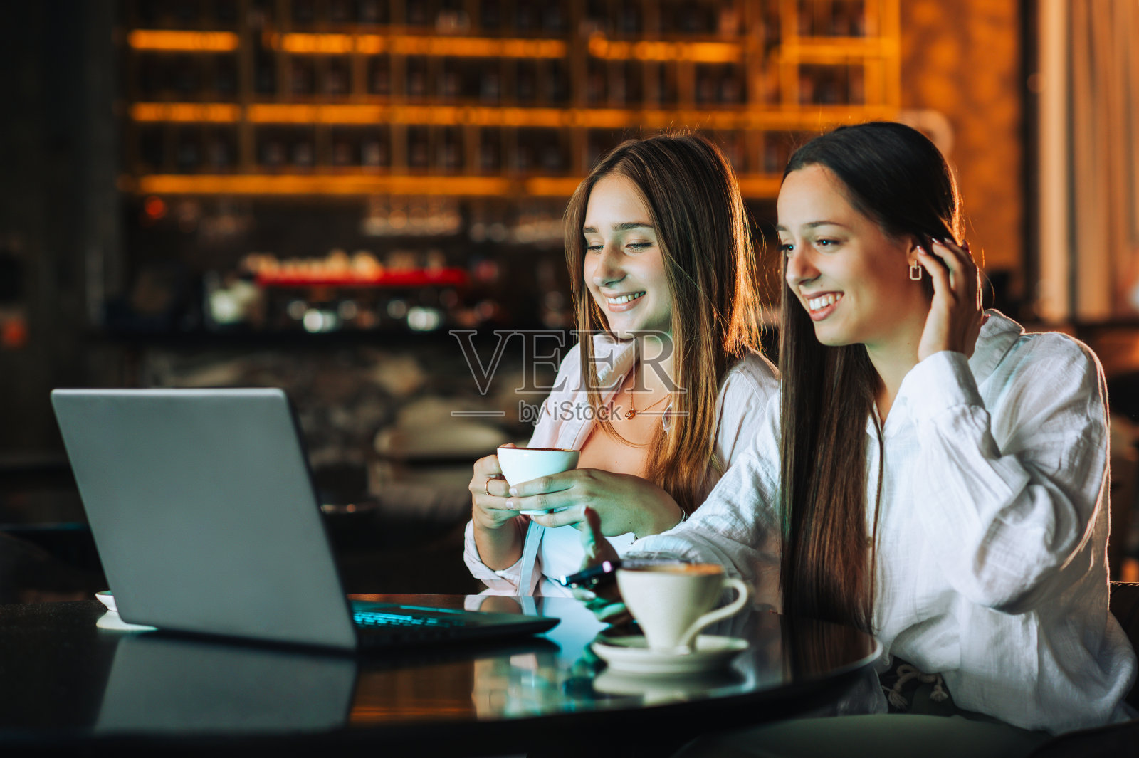 两个朋友坐在咖啡店里开电话会议照片摄影图片