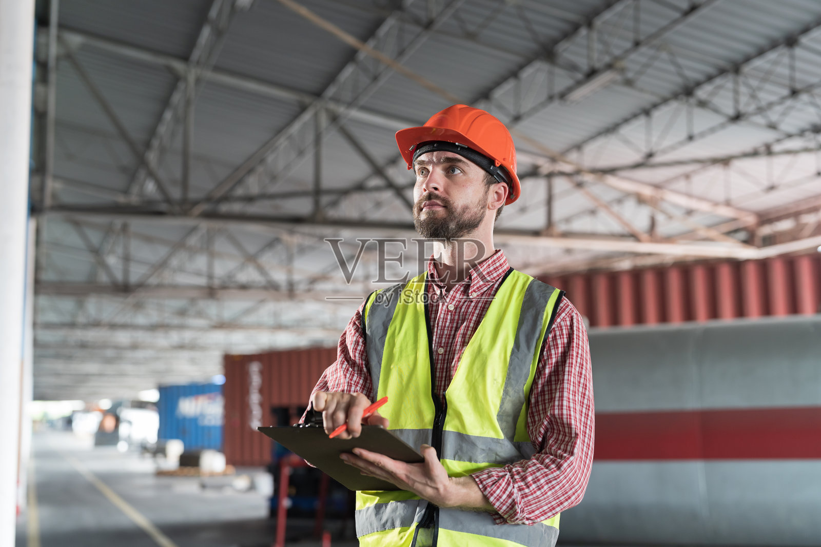 男仓库工人在仓库工作时拿着剪贴板。仓库工人检查产品质量并检查库存照片摄影图片