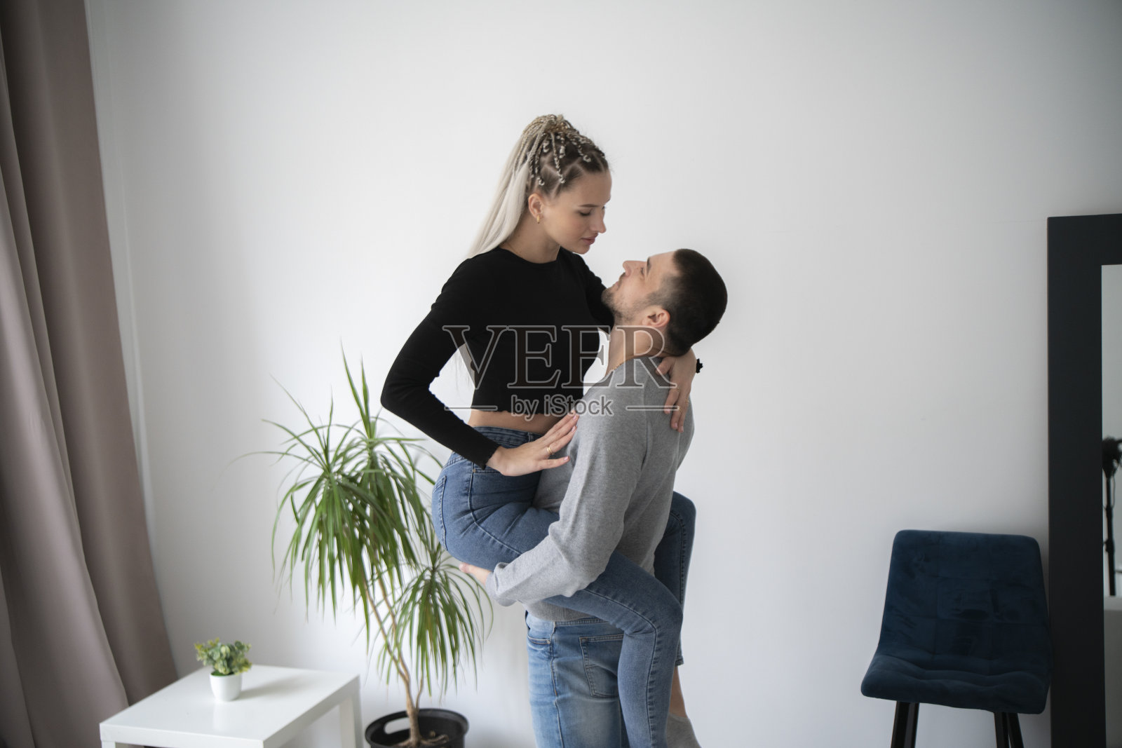 年轻男子抱着一个微笑的女人在明亮的室内，一起玩得很开心照片摄影图片