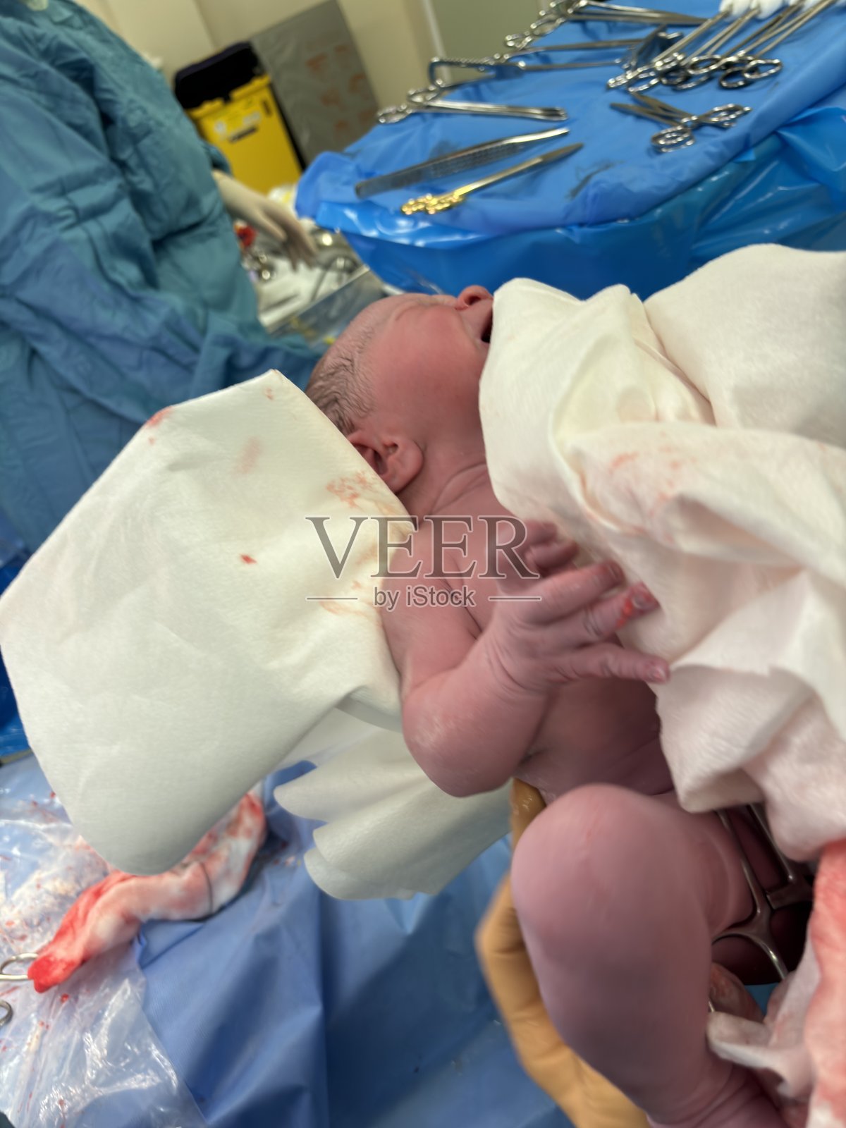 在医院的产房里，一个刚出生的男婴在剖腹产后不久。父母亲都在房间里。照片摄影图片