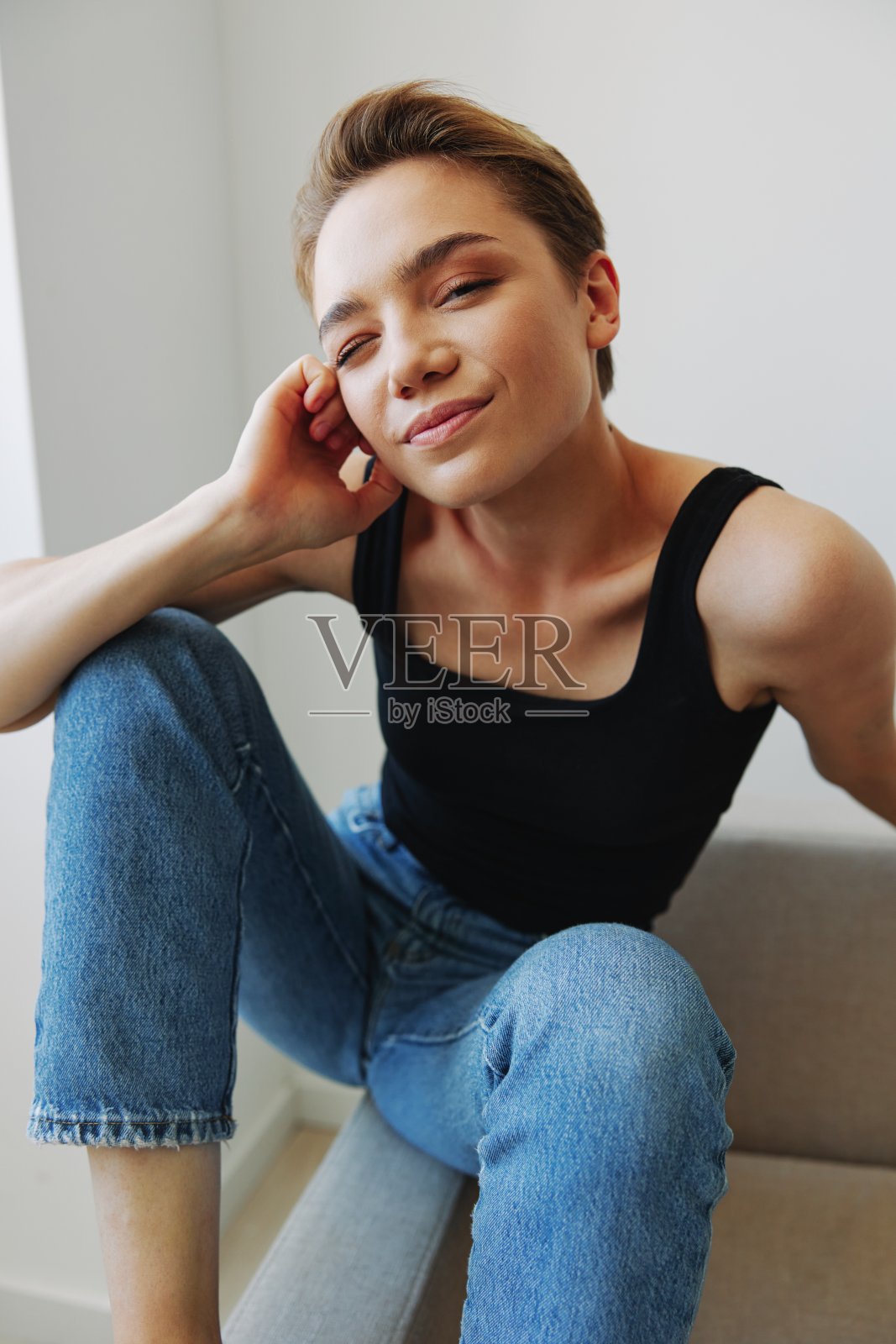 年轻女子短发的头发有乐趣在家里的沙发上微笑和幸福，在家里度假，自然摆姿势没有过滤器，自由的复制空间照片摄影图片