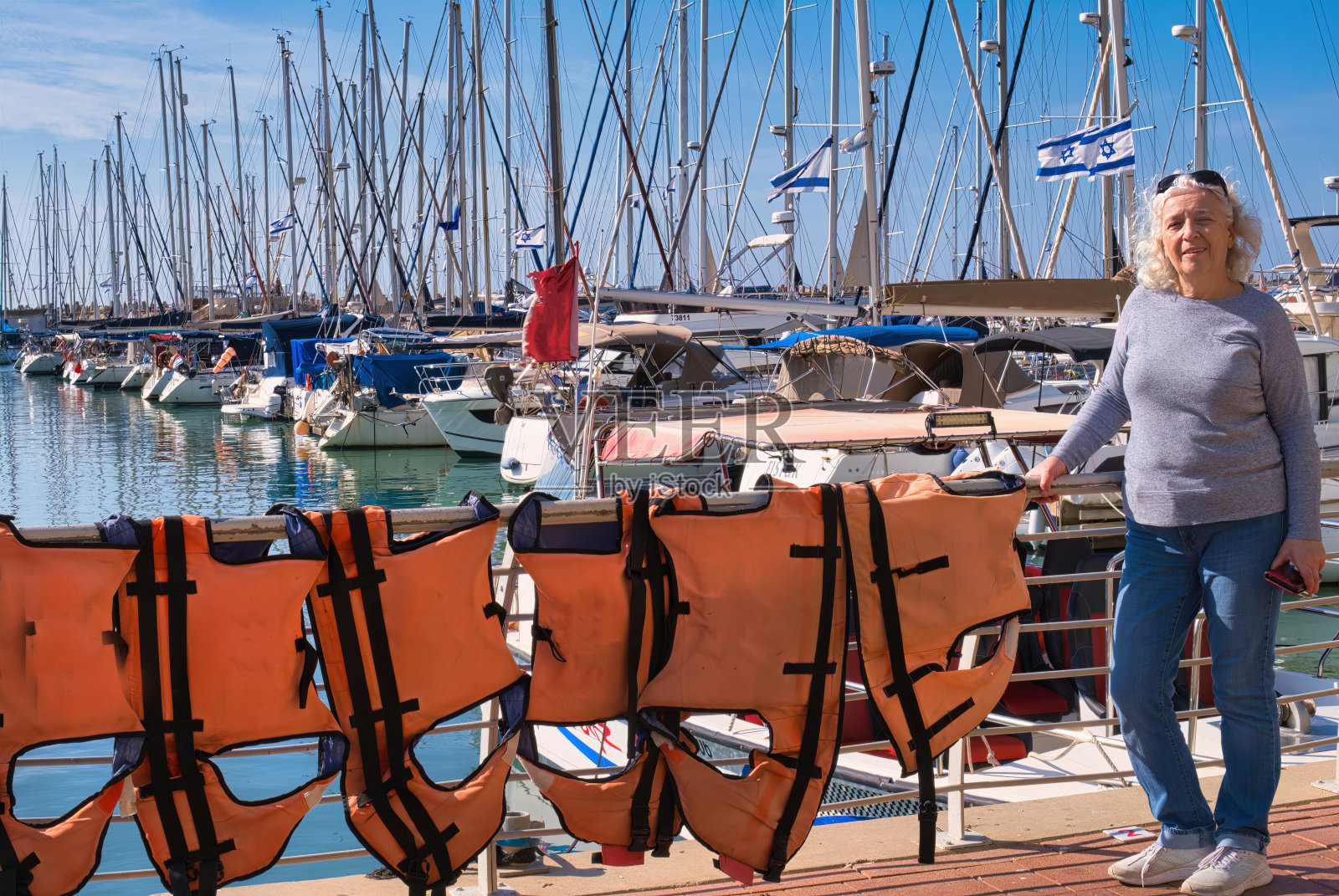 夏天，高级女士和救生衣在游艇俱乐部码头的栏杆上晒干。照片摄影图片