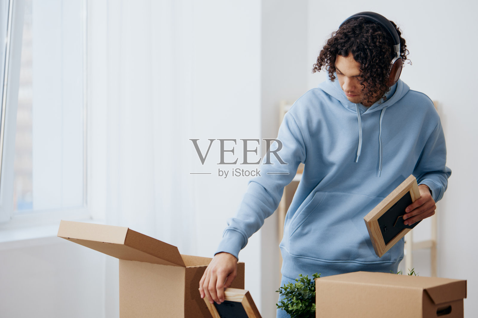 一个年轻人正在从房间里的箱子里拆东西照片摄影图片