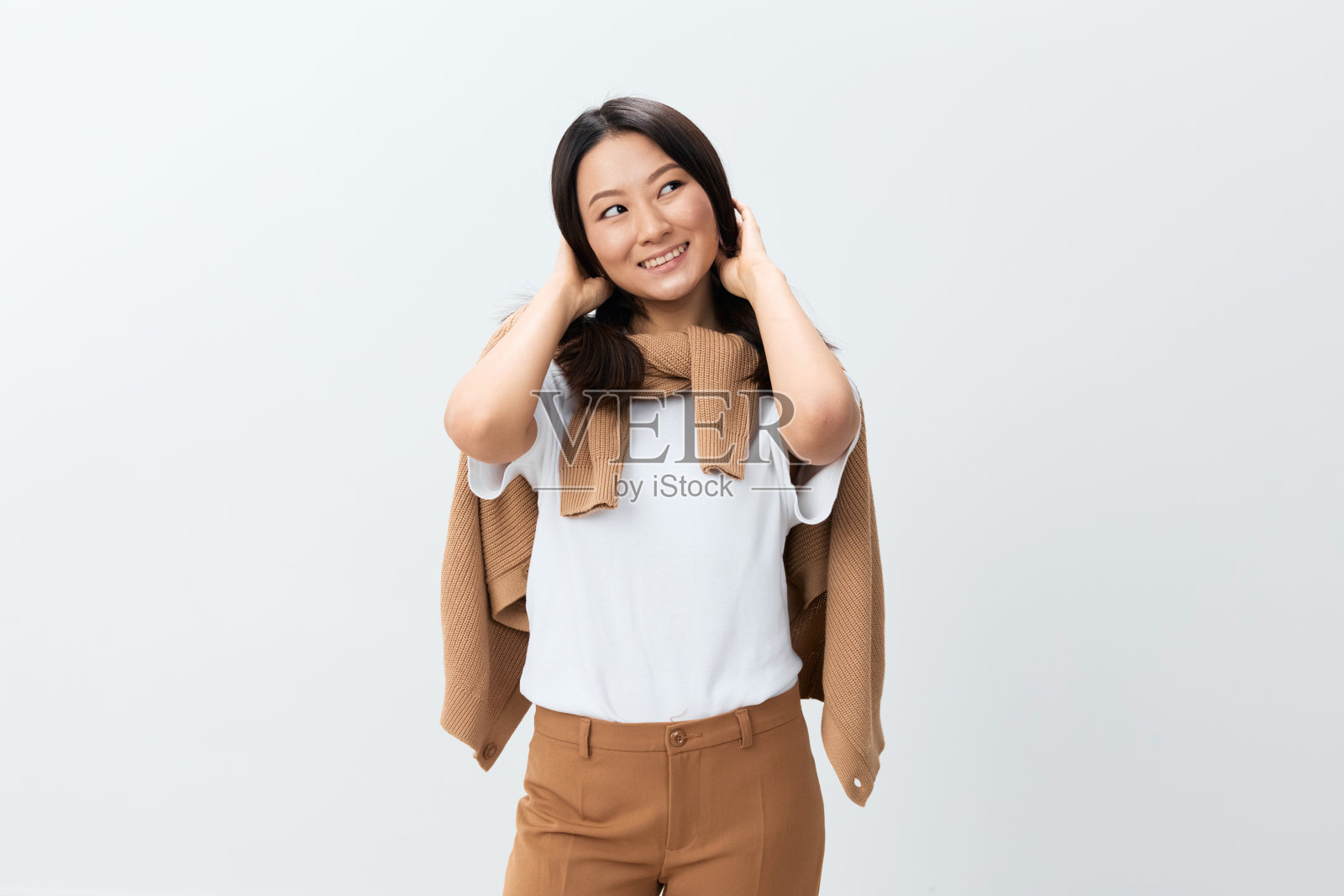 喜欢微笑的可爱的韩国年轻女性穿着米色温暖的毛衣，在白色的工作室背景上独自摆姿势。最好的广告报价。秋季风格概念。季节性销售照片摄影图片