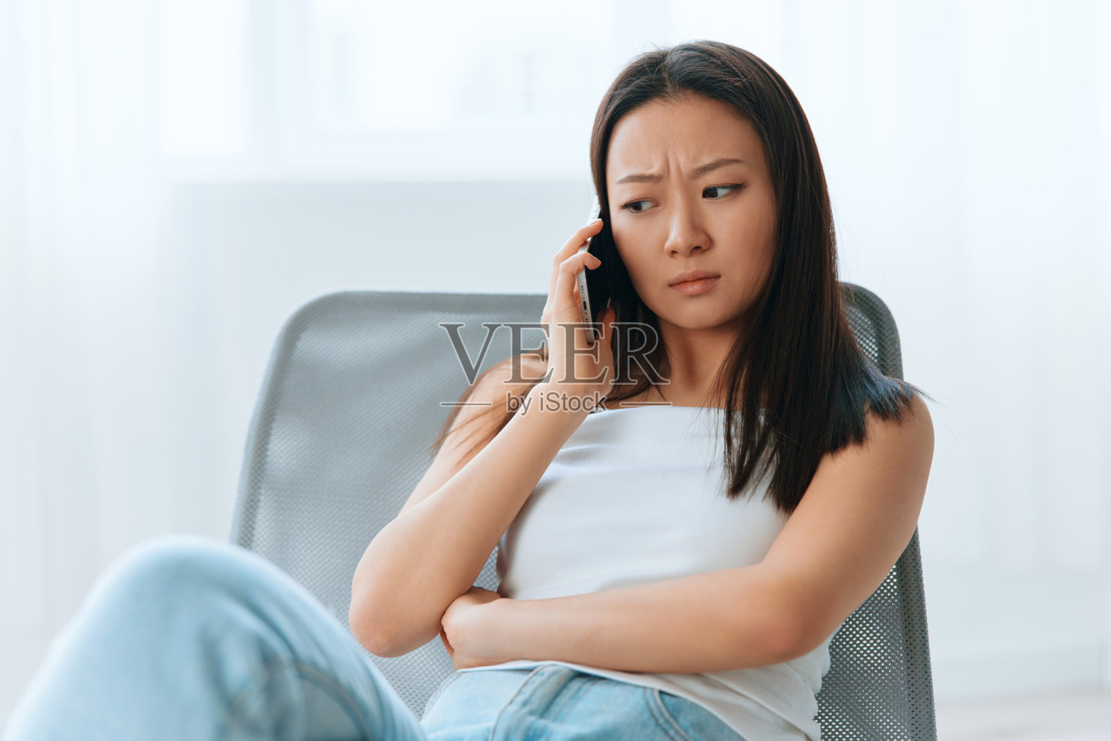 困惑、沮丧、黝黑、可爱的年轻亚洲女子在家里室内客厅用电话听到震惊的消息。远程通信社交媒体概念。酷报价横幅广角照片摄影图片