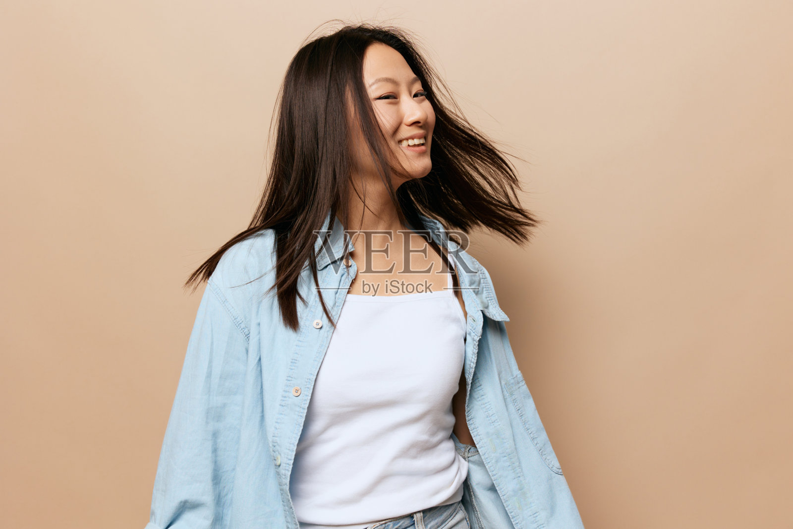 跳舞欢快的古铜色可爱的年轻亚洲女士旋转挥舞着她的头发摆出孤立的米色柔和的背景。人与情感。幸福的概念。复制空间报价横幅。照片摄影图片