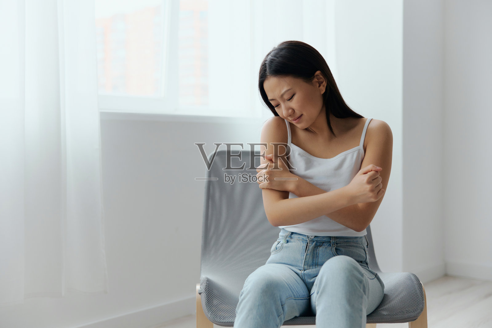 虐待的受害者。哭泣受苦晒黑美丽的年轻亚洲女子碰肩拥抱自己在家里室内客厅。伤害，不良健康，疾病概念。酷炫报价横幅照片摄影图片