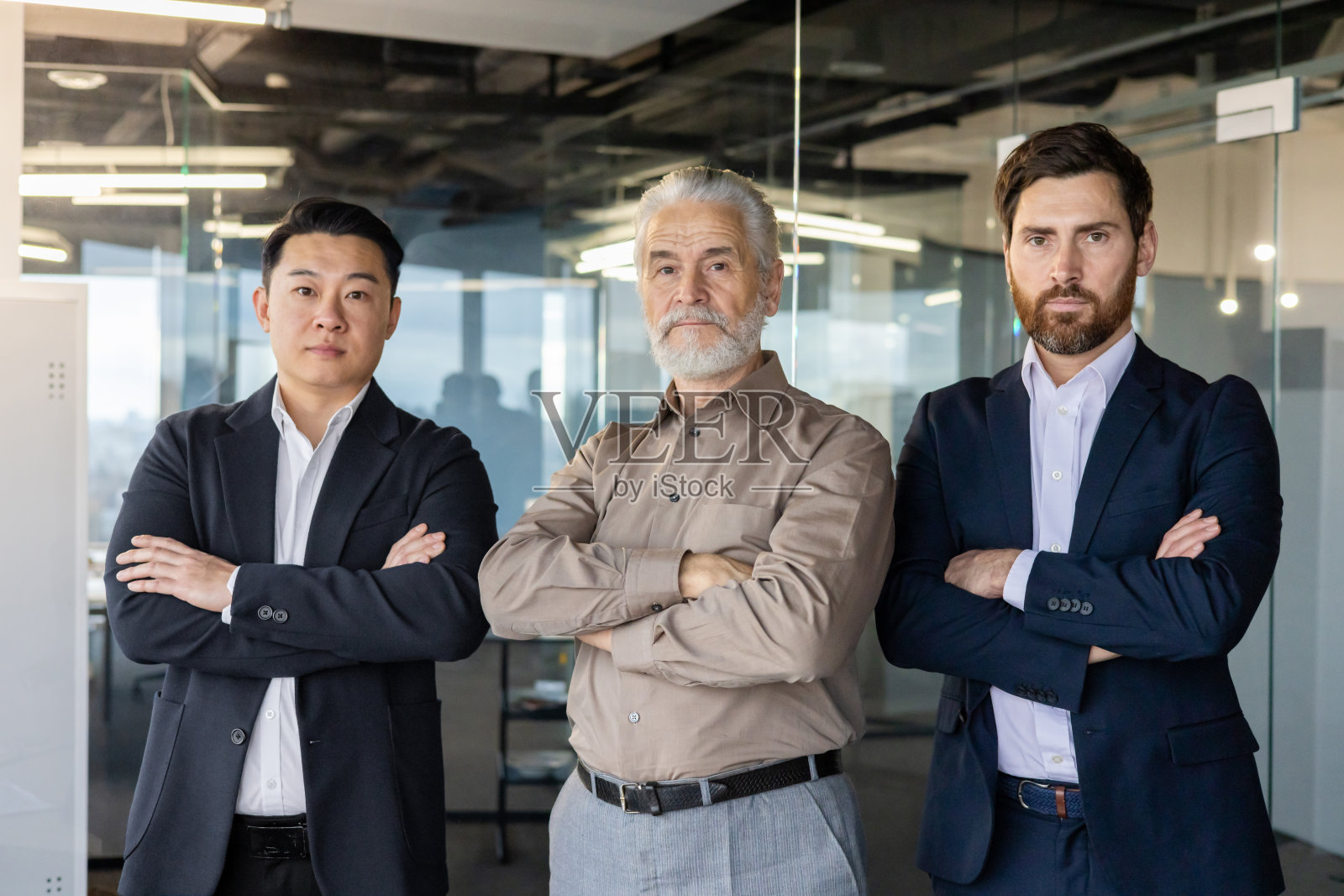 商人的肖像，跨种族和跨年龄的团队，合作伙伴站在办公室，交叉手臂在胸前，自信而认真地看着镜头照片摄影图片