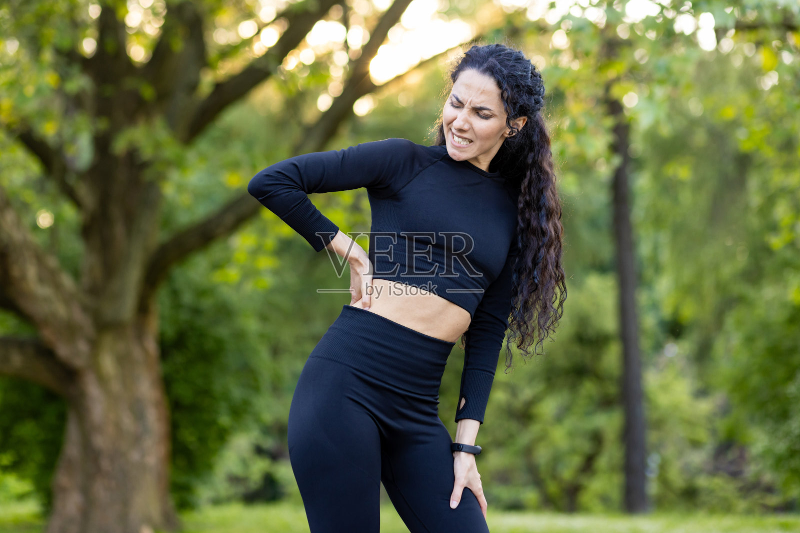 西班牙裔妇女在户外锻炼时背部疼痛照片摄影图片