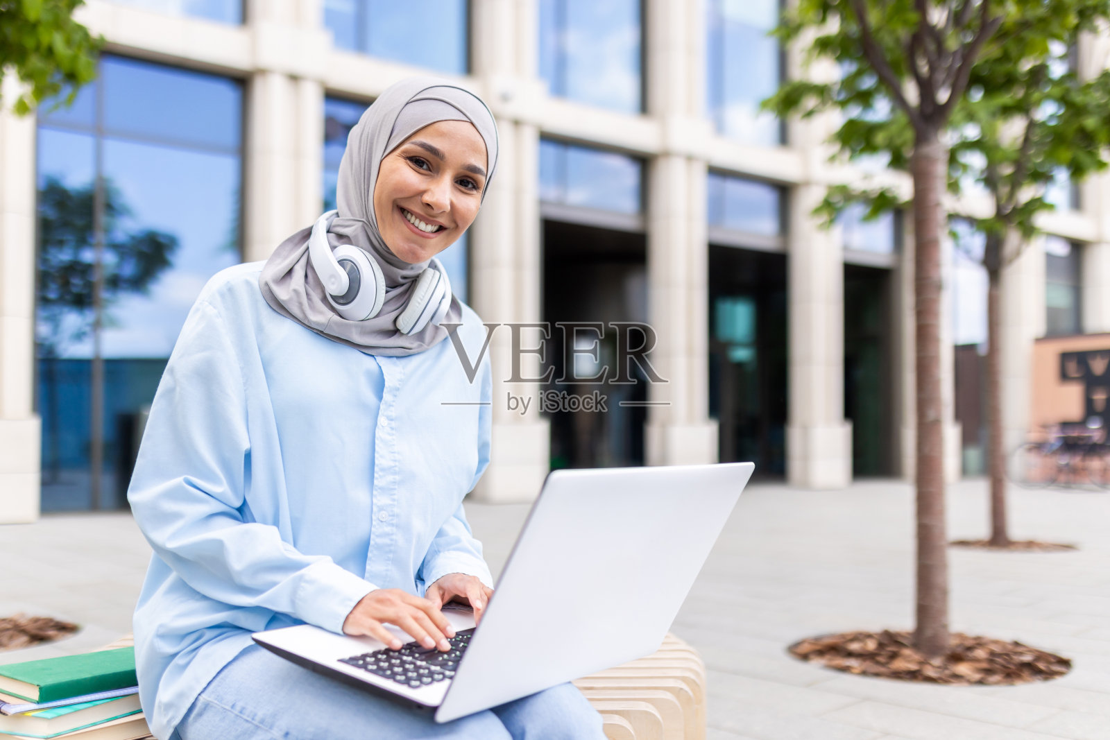 微笑的穆斯林妇女在办公大楼附近户外使用笔记本电脑照片摄影图片