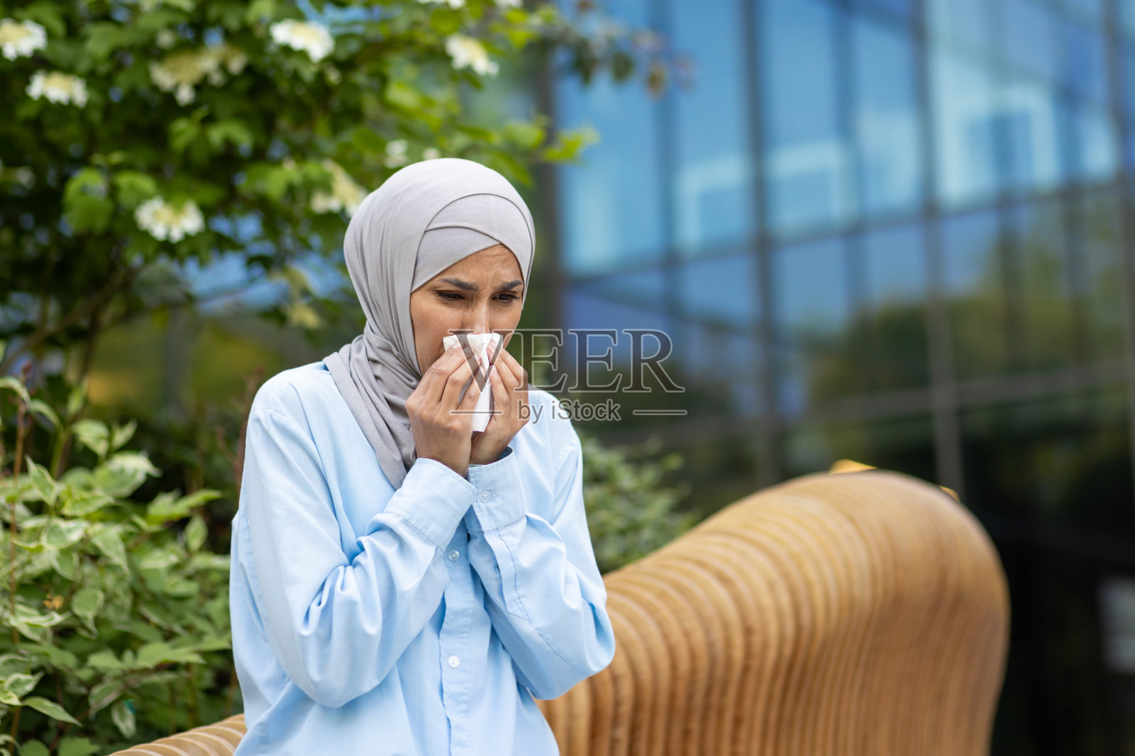 戴头巾的妇女在户外对着纸巾打喷嚏照片摄影图片