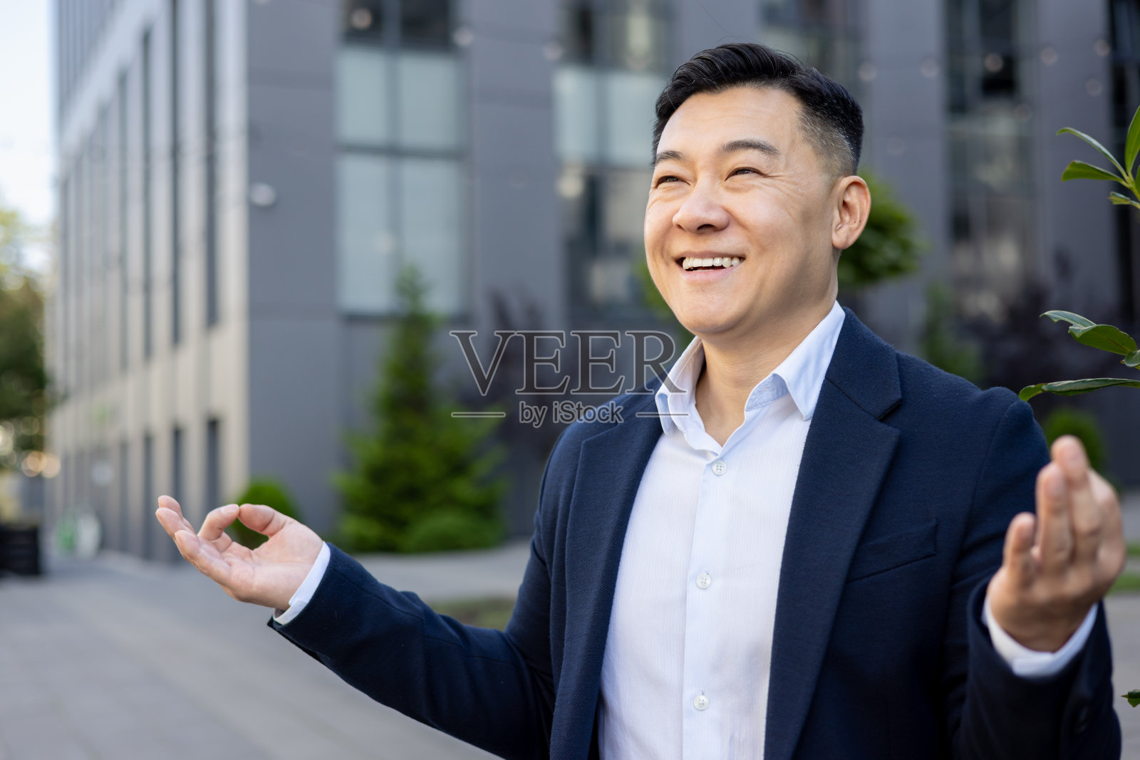 微笑的年轻亚洲男商人在办公中心外，站在瑜伽和莲花姿势，冥想和休息照片摄影图片