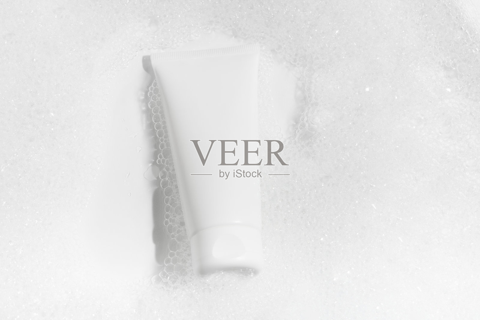 白色的模型一管奶油在水中与泡沫在白色的背景。概念的洗涤凝胶，保湿霜，化妆品美容和自我护理。图片为您的设计照片摄影图片