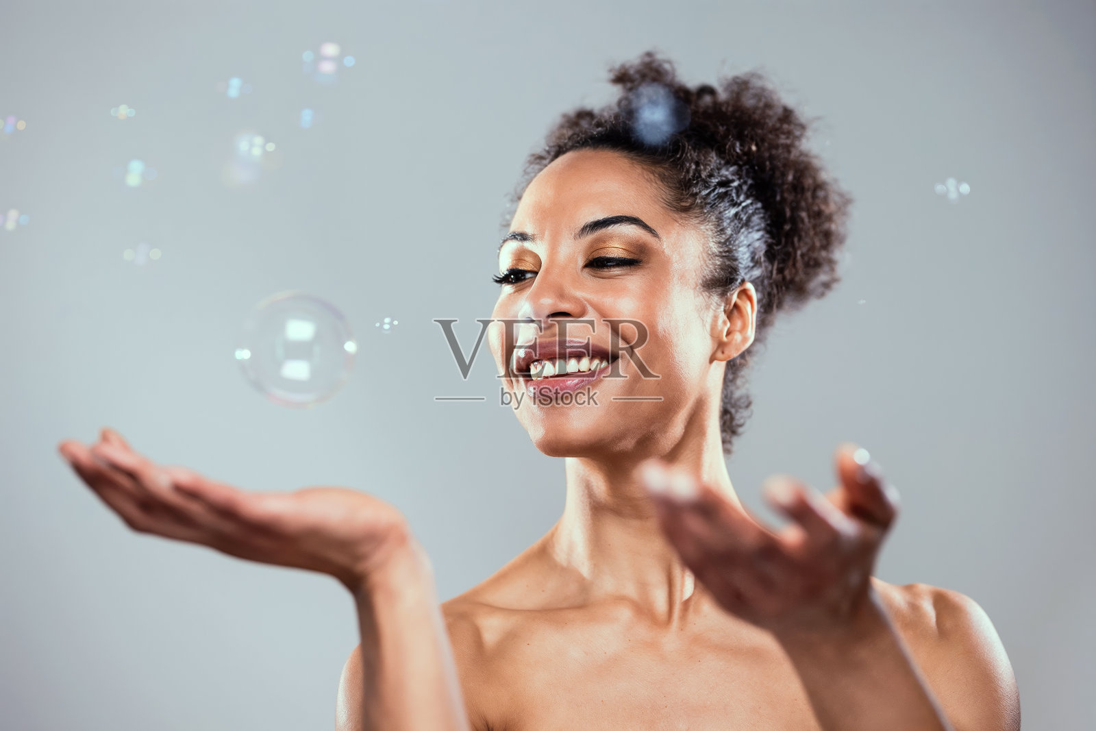 迷人的成熟女人在孤立的白色上玩肥皂和水泡的镜头照片摄影图片