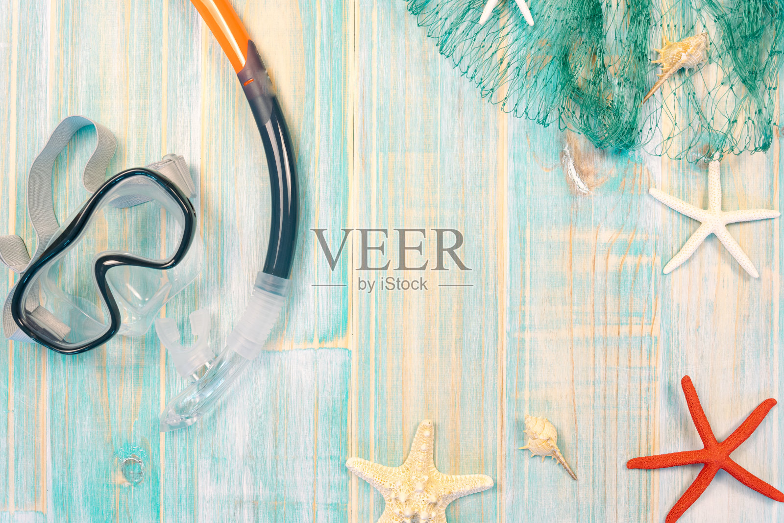 暑假潜水和海滩的概念。组成潜水镜，通气管和渔网与海星剥离蓝色木制背景照片摄影图片