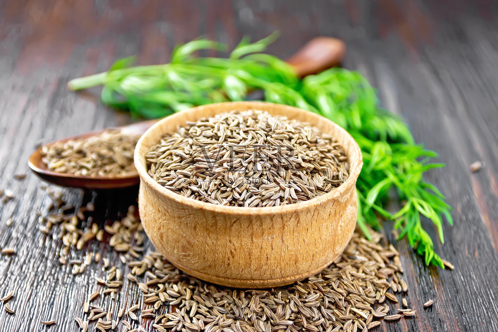 小茴香籽放入碗中，勺子中加入香草照片摄影图片