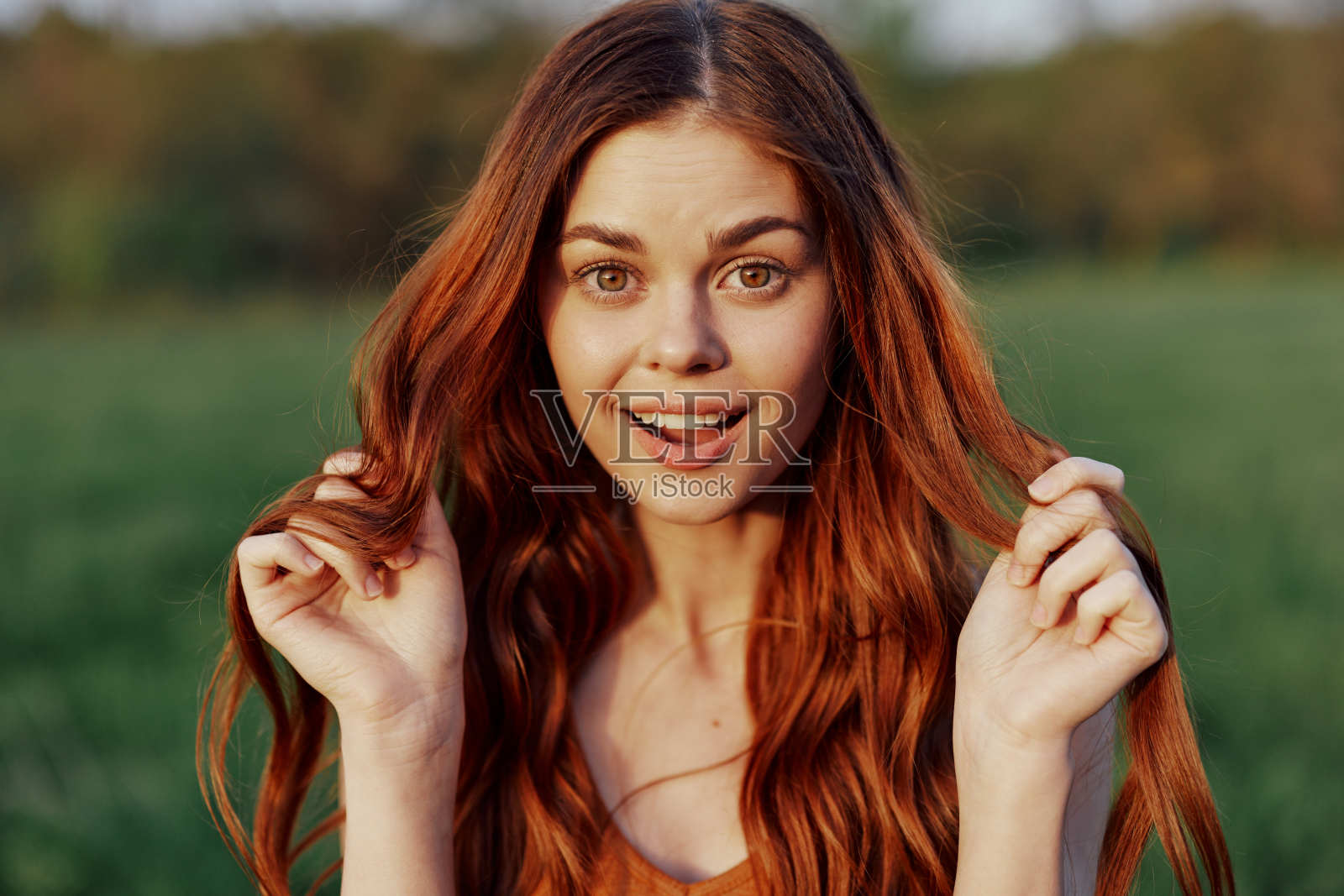 在夕阳的照耀下，一个美丽的女人在大自然中对着镜头微笑。美与自然和谐相处的理念照片摄影图片