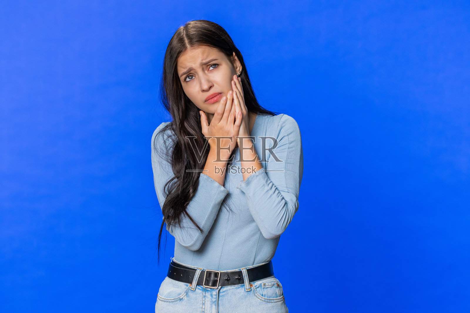 年轻女子摸着脸颊，闭着眼睛，表情可怕，牙疼得要命照片摄影图片