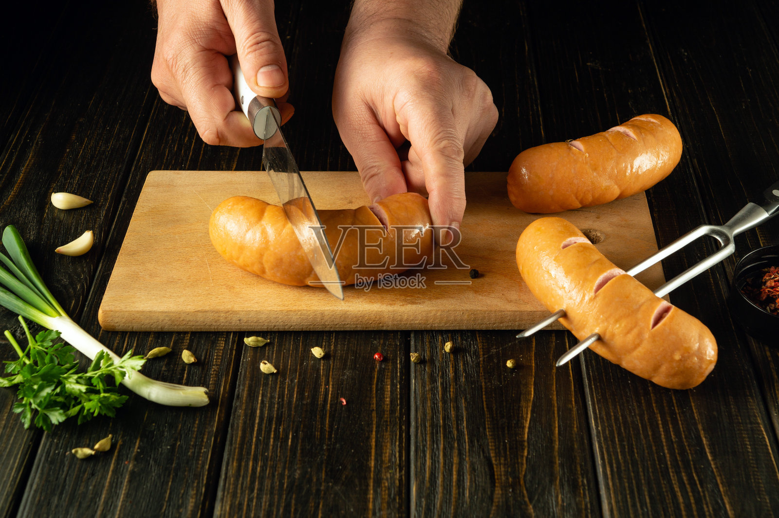 厨师正在厨房板上准备维也纳香肠。低调的烧烤概念，香肠和芳香香料。欧洲菜照片摄影图片