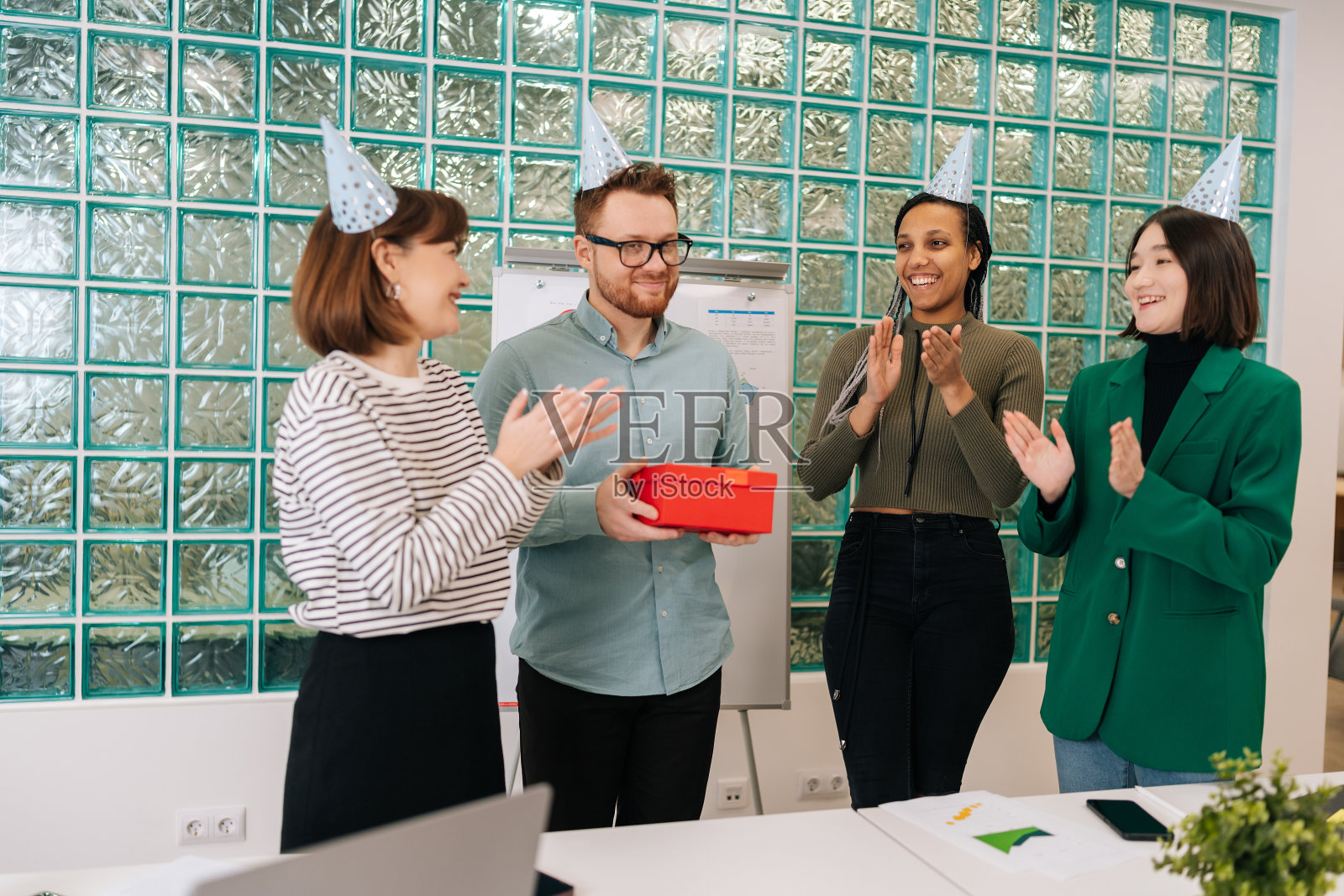 创业公司欢快的多民族年轻员工庆祝生日，向快乐的英俊同事分发礼盒。照片摄影图片