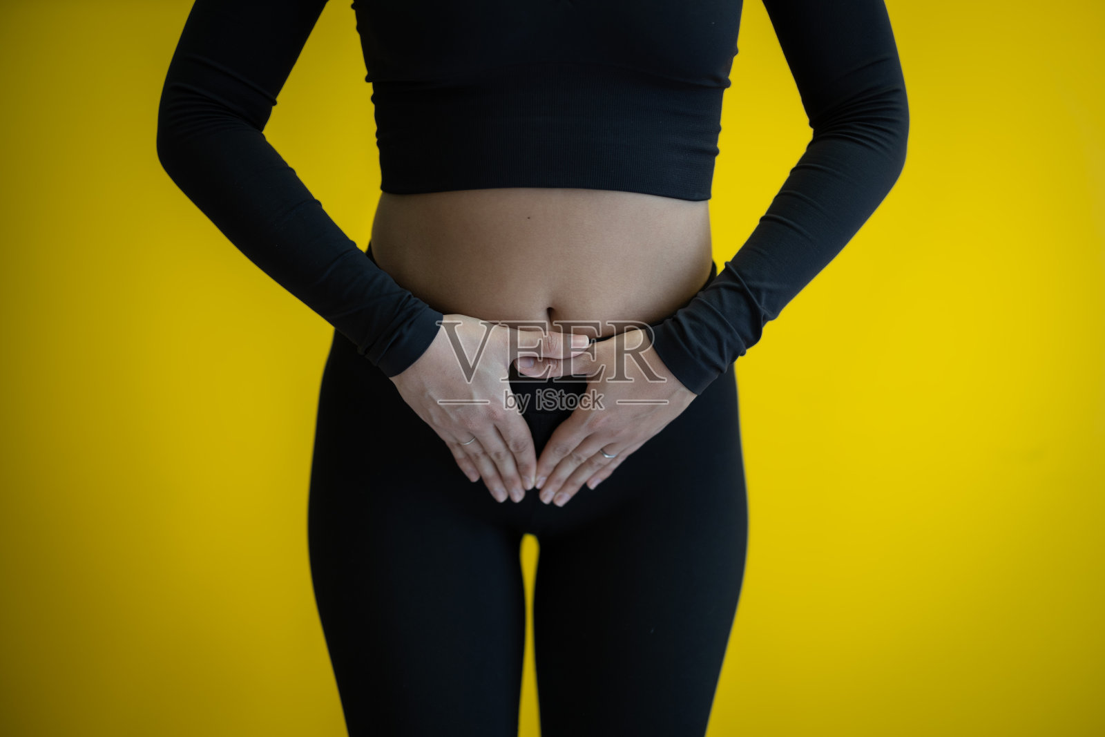 年轻女性弓着腰捂着肚子，可能需要上厕所，描绘腹部健康或痛苦。照片摄影图片