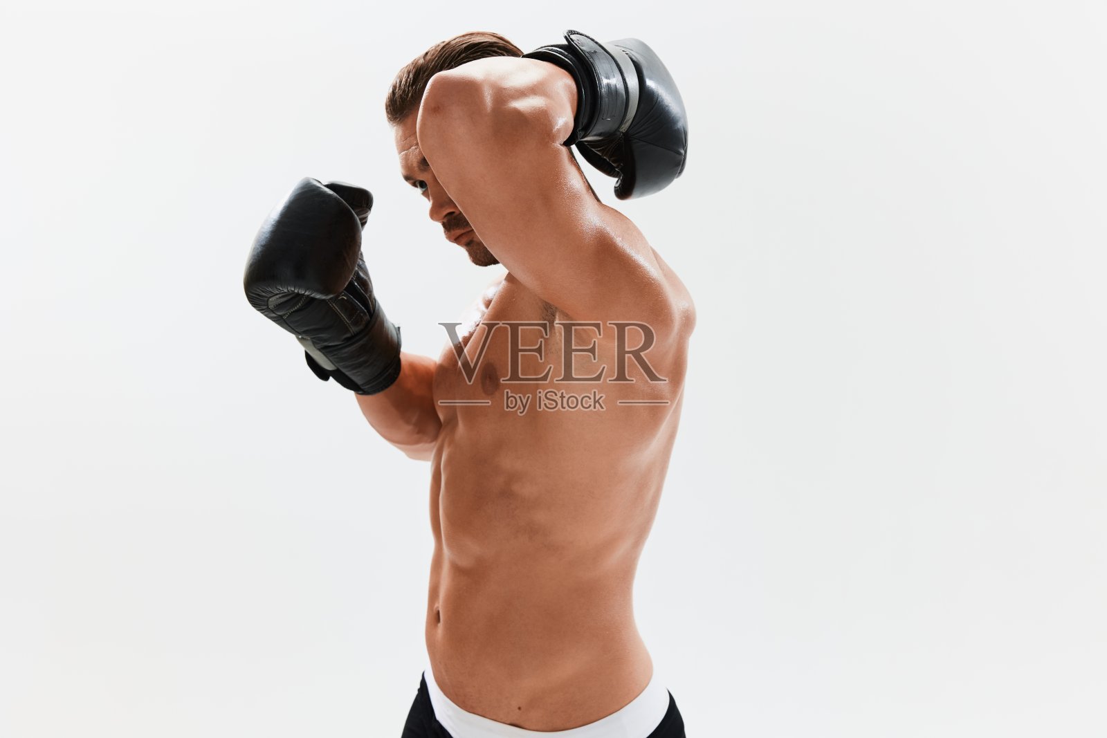 男子健美运动员摆姿势，在拳击手套与躯干腹肌在全长背景，拳击和武术。广告，运动，积极的生活方式，竞争，挑战的理念。照片摄影图片