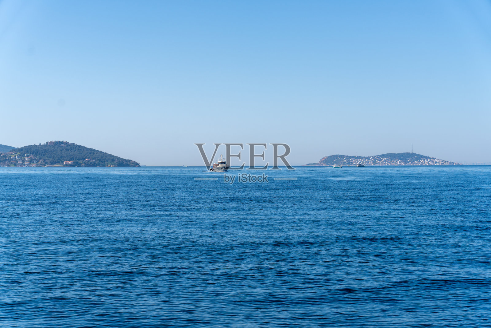 一艘船在大海上航行，背景是湛蓝的天空照片摄影图片