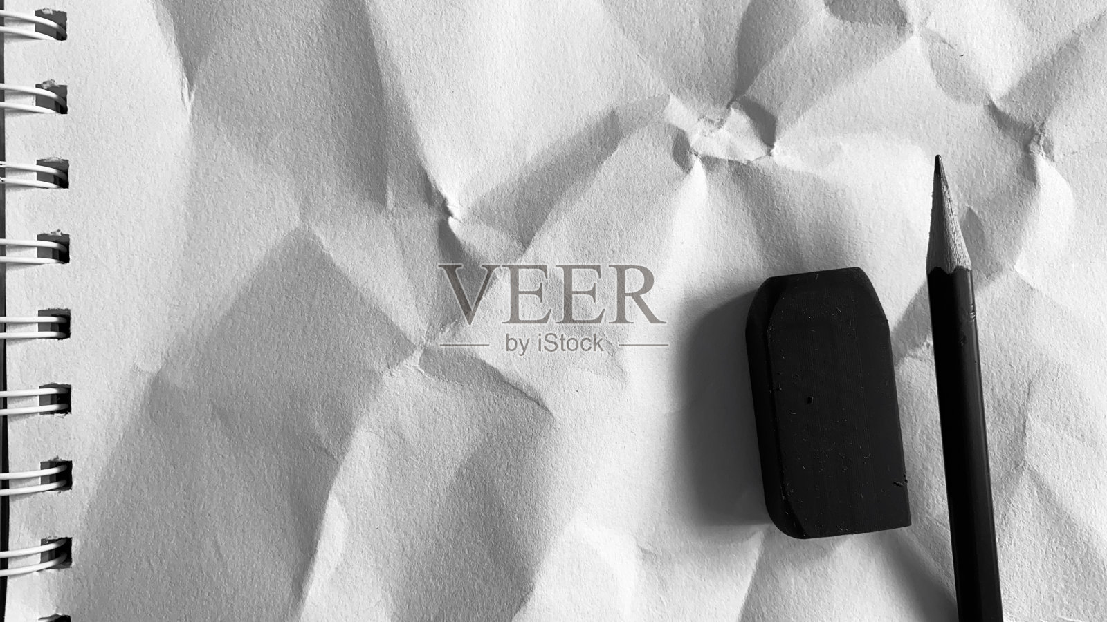 桌子上有黑白照片、铅笔和笔记本。照片摄影图片