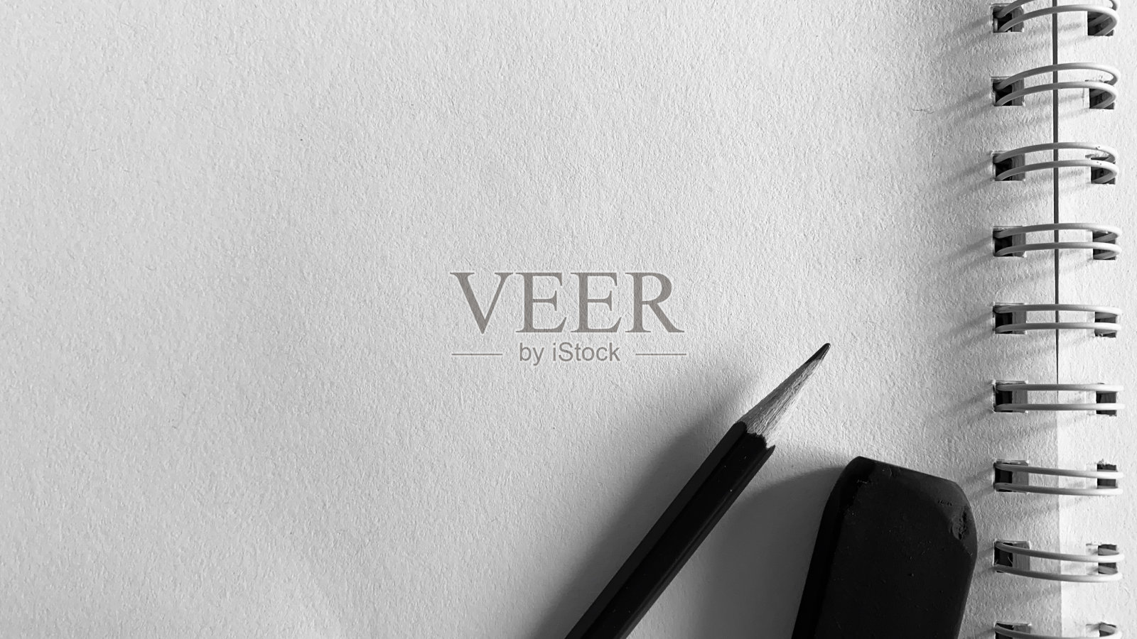 桌子上有黑白照片、铅笔和笔记本。照片摄影图片