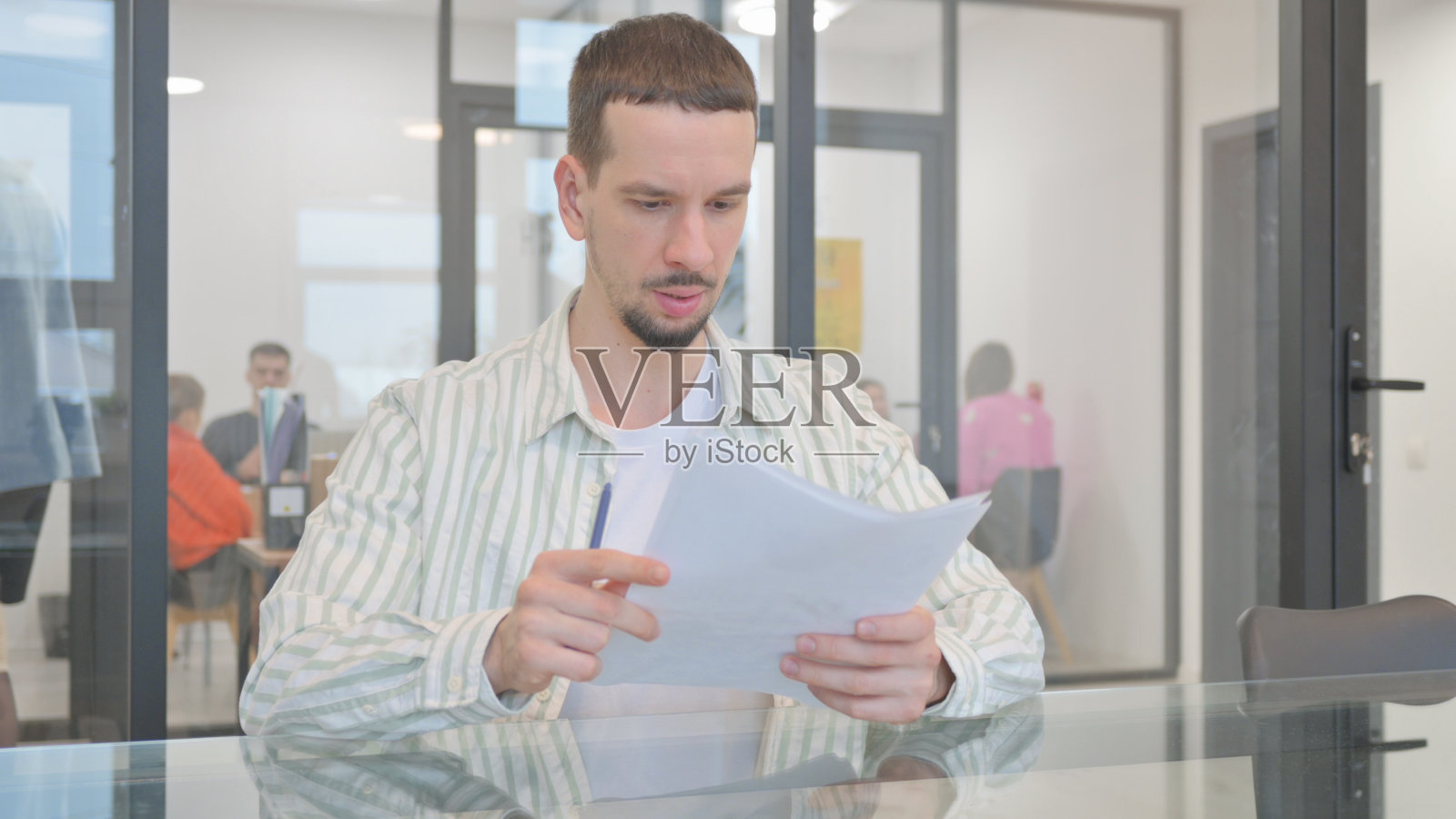 有创造力的年轻人在工作中阅读文件照片摄影图片